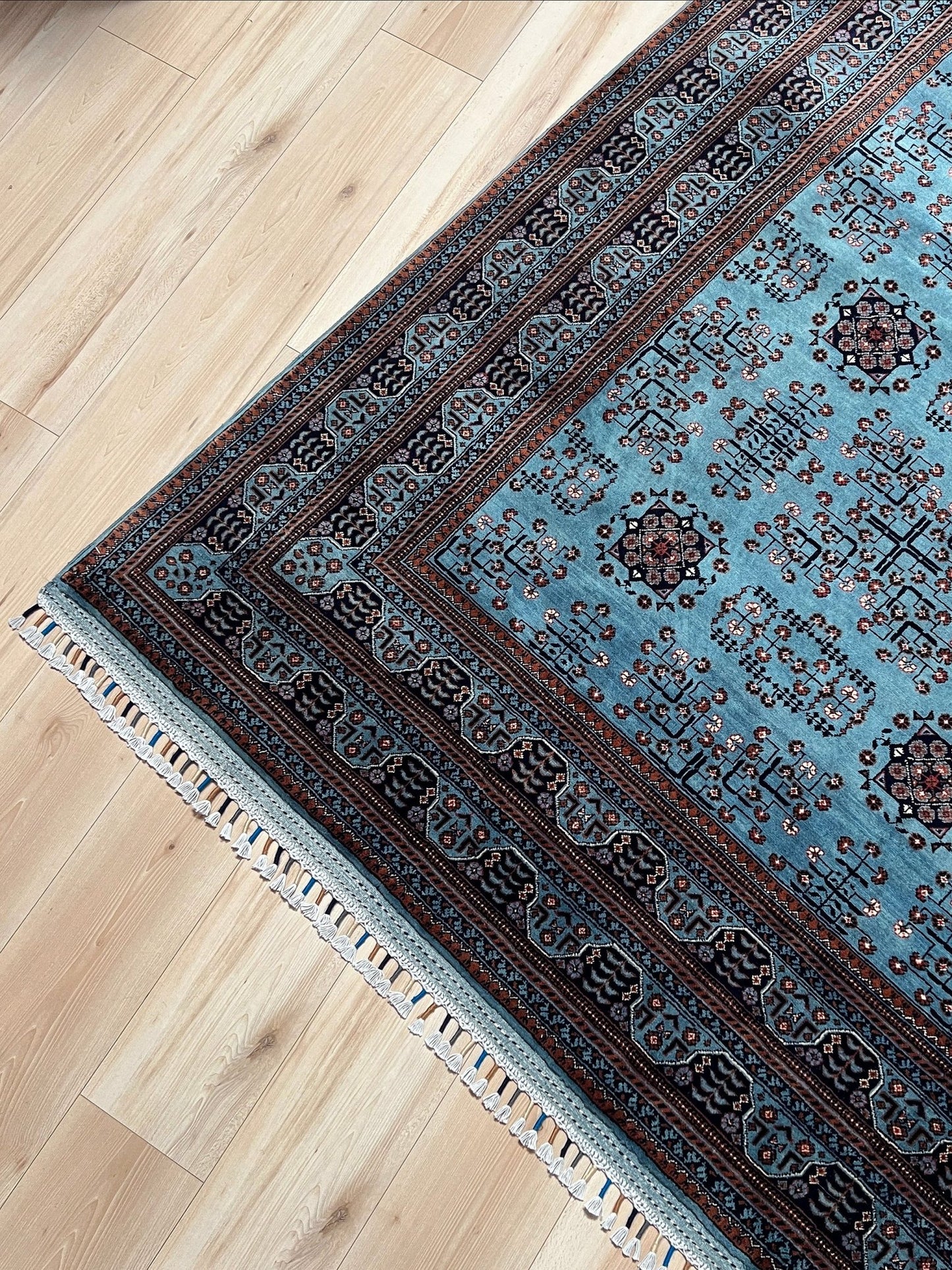 Corner detail of the Handmade Turkmen rug with a baby blue ground, featuring traditional geometric motifs in brown, red, and white, crafted from silky Ghazni wool with a luxurious sheen, available with free shipping from the best handmade rug shop in the San Francisco Bay Area.