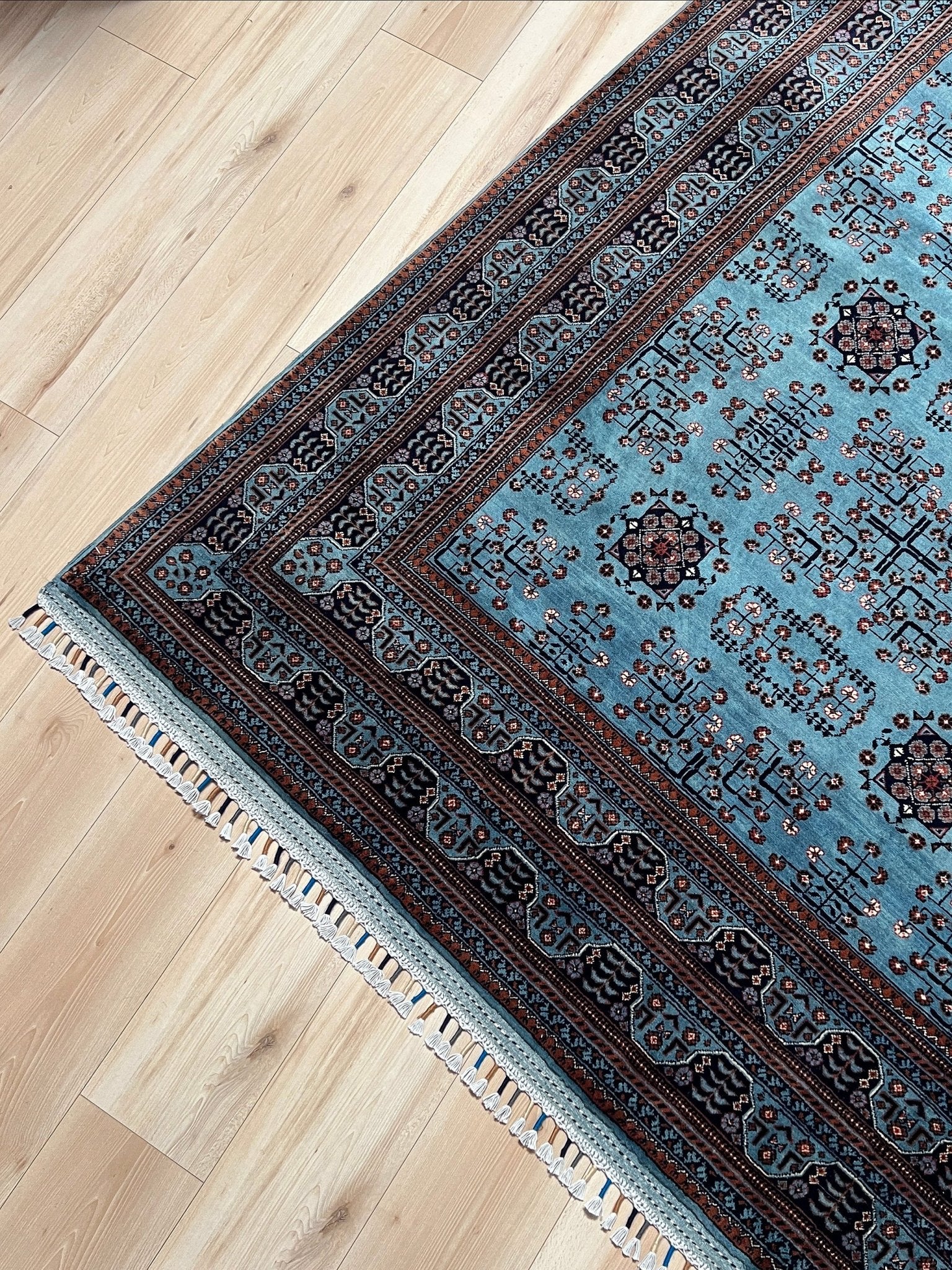 Corner detail of the Handmade Turkmen rug with a baby blue ground, featuring traditional geometric motifs in brown, red, and white, crafted from silky Ghazni wool with a luxurious sheen, available with free shipping from the best handmade rug shop in the San Francisco Bay Area.