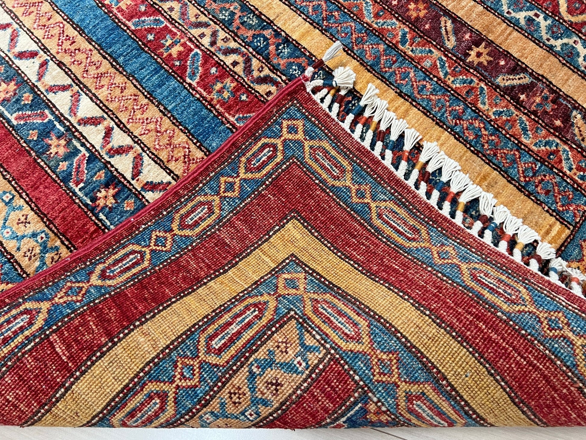 Back of Handmade Turkish Shawl Rug with vibrant vertical stripes in red, blue, yellow, and cream, featuring intricate tribal motifs from the best luxury rug shop in the San Francisco Bay Area. High-quality wool rug at an affordable price with free shipping. Perfect for adding a touch of Turkish craftsmanship to any room. Ideal statement piece for living rooms, bedrooms, and entryways.