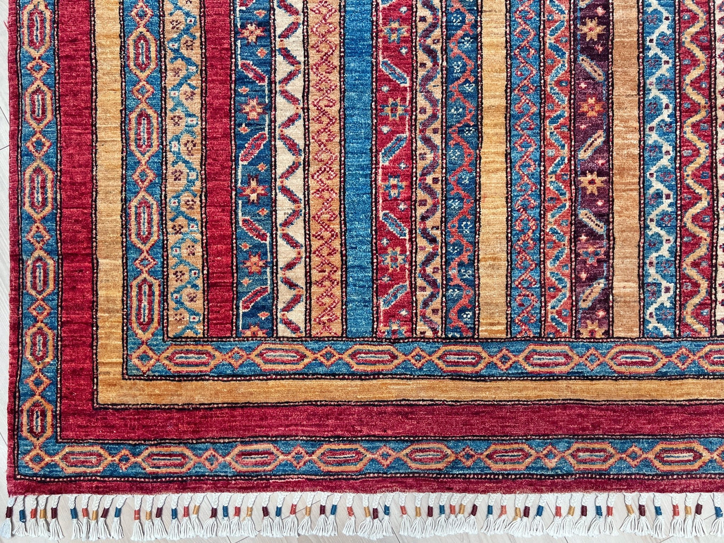 Corner detail Handmade Turkish Shawl Rug with vibrant vertical stripes in red, blue, yellow, and cream, featuring intricate tribal motifs from the best luxury rug shop in the San Francisco Bay Area. High-quality wool rug at an affordable price with free shipping. Perfect for adding a touch of Turkish craftsmanship to any room. Ideal statement piece for living rooms, bedrooms, and entryways.