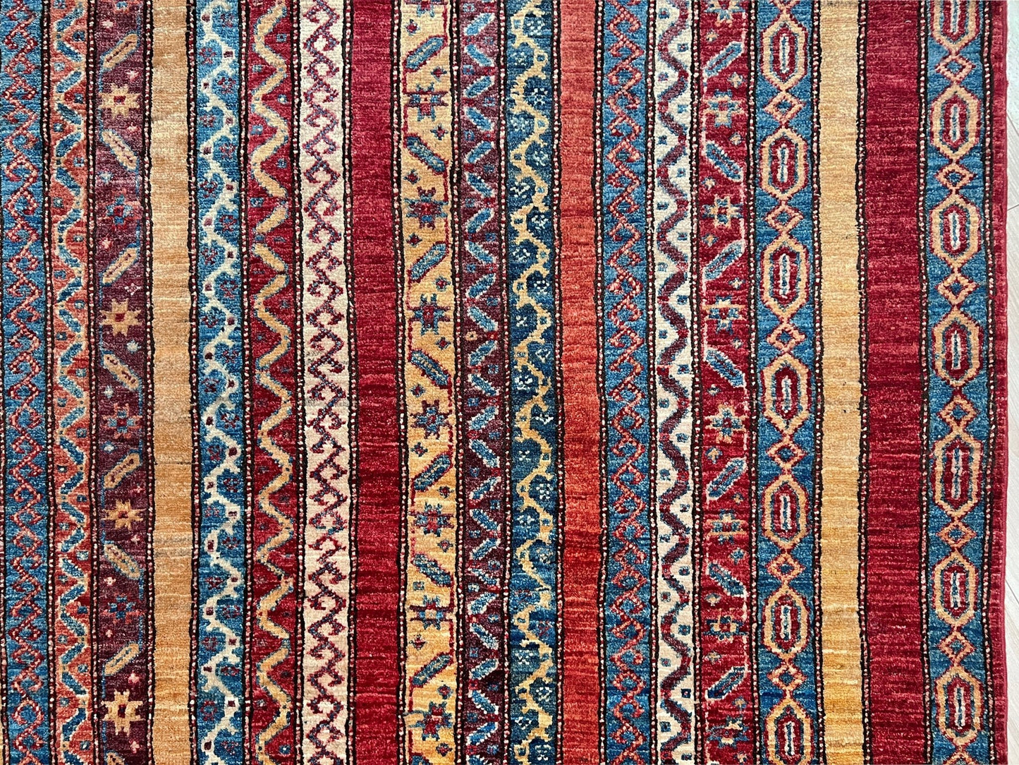 Detail of Handmade Turkish Shawl Rug with vibrant vertical stripes in red, blue, yellow, and cream, featuring intricate tribal motifs from the best luxury rug shop in the San Francisco Bay Area. High-quality wool rug at an affordable price with free shipping. Perfect for adding a touch of Turkish craftsmanship to any room. Ideal statement piece for living rooms, bedrooms, and entryways.