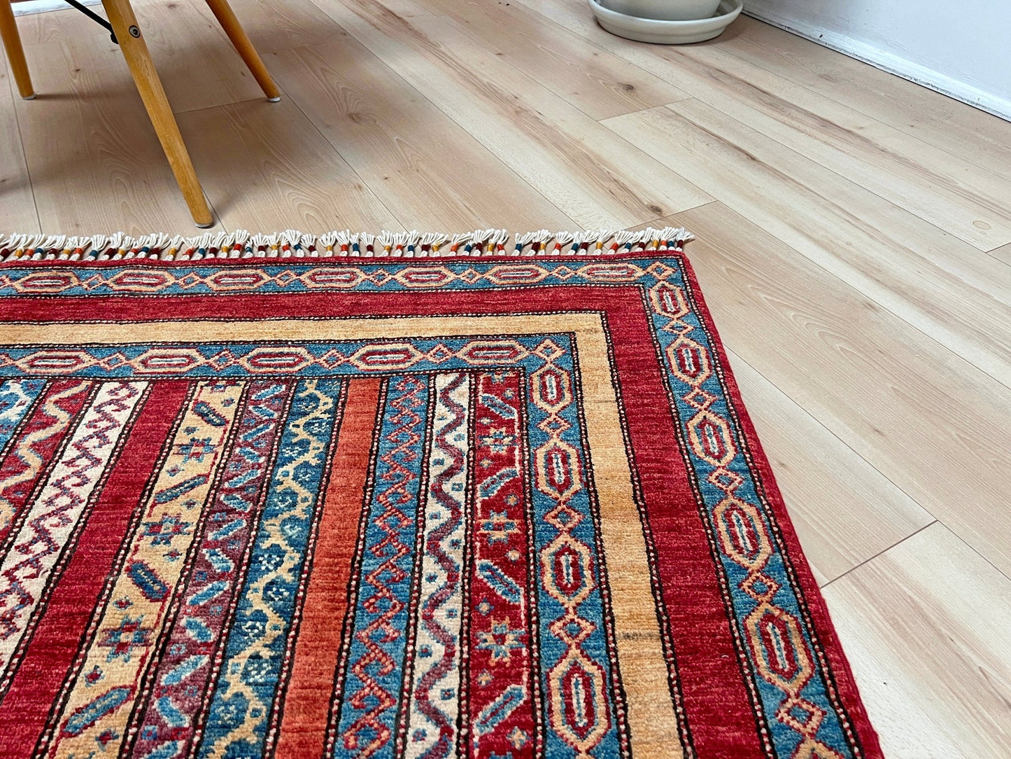 Corner detail of Handmade Turkish Shawl Rug with vibrant vertical stripes in red, blue, yellow, and cream, featuring intricate tribal motifs from the best luxury rug shop in the San Francisco Bay Area. High-quality wool rug at an affordable price with free shipping. Perfect for adding a touch of Turkish craftsmanship to any room. Ideal statement piece for living rooms, bedrooms, and entryways.