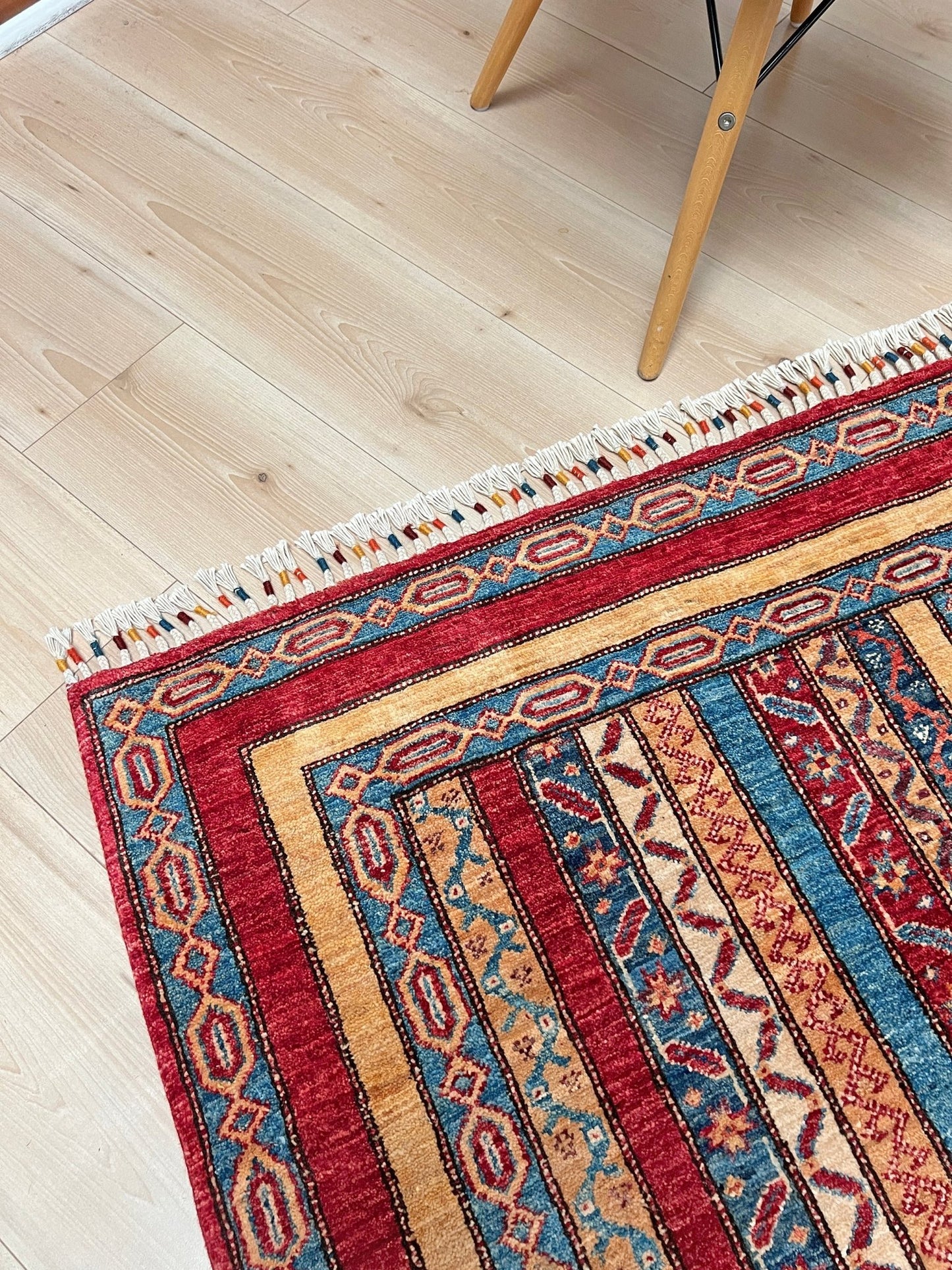 Corner detail of Handmade Turkish Shawl Rug with vibrant vertical stripes in red, blue, yellow, and cream, featuring intricate tribal motifs from the best luxury rug shop in the San Francisco Bay Area. High-quality wool rug at an affordable price with free shipping. Perfect for adding a touch of Turkish craftsmanship to any room. Ideal statement piece for living rooms, bedrooms, and entryways.