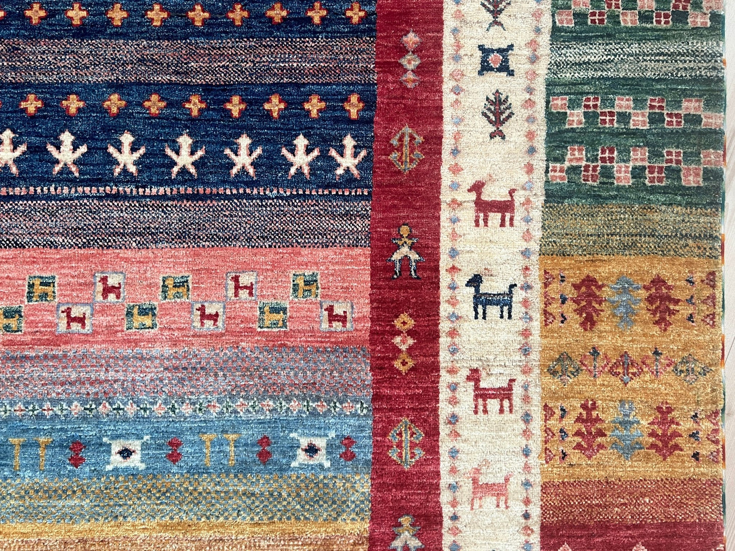 Border of Colorful handmade Gabbeh rug with animal motifs in rich brick red, soft sky blue, teal, golden mustard yellow, forest green, and cream hues from the best luxury handmade rug shop in the San Francisco Bay Area. Premium quality wool rug featuring vibrant stripes and tribal design elements. Perfect as a statement piece for living rooms and cozy spaces. Free shipping available.