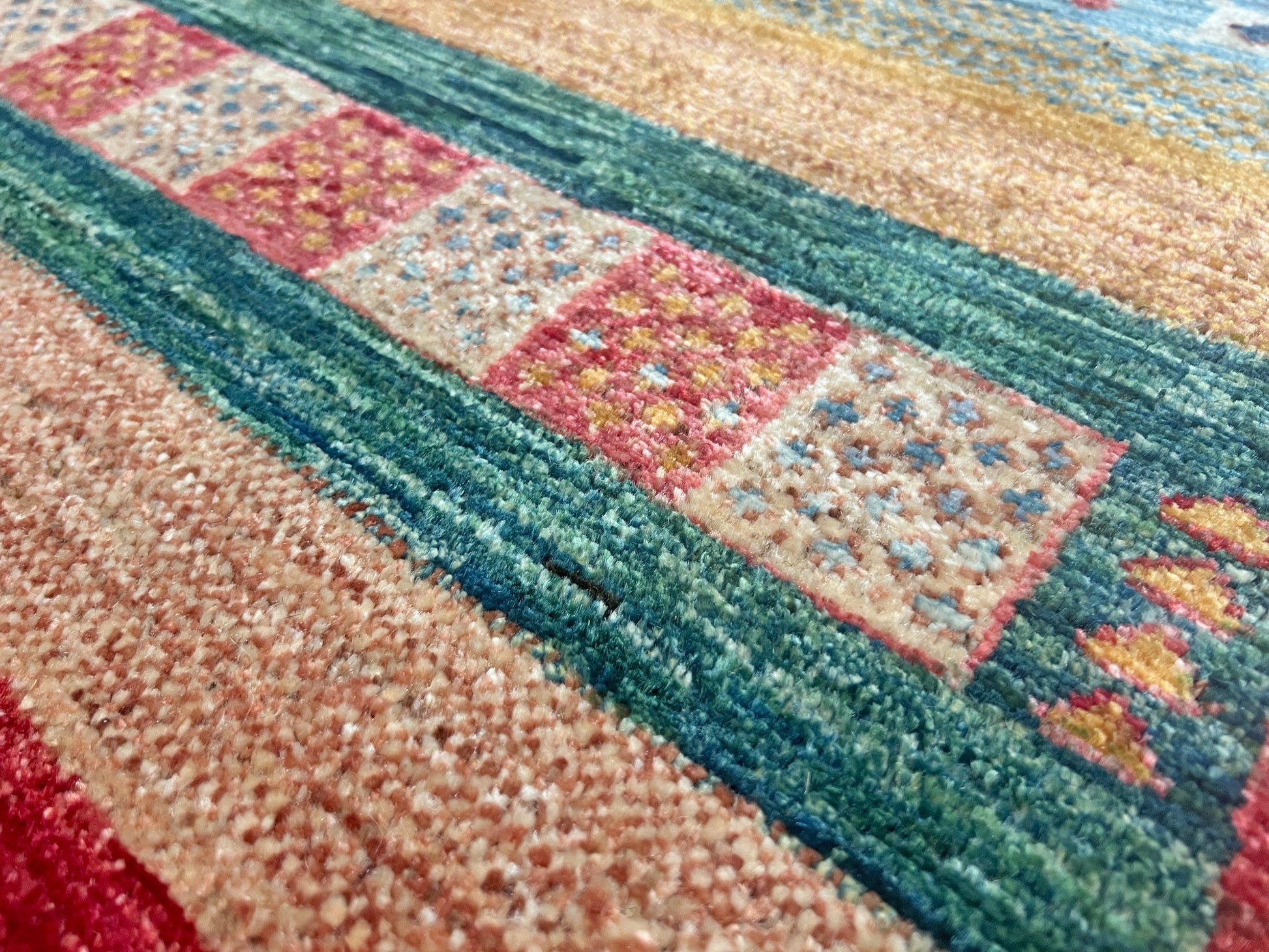 Close up of Colorful handmade Gabbeh rug with animal motifs in rich brick red, soft sky blue, teal, golden mustard yellow, forest green, and cream hues from the best luxury handmade rug shop in the San Francisco Bay Area. Premium quality wool rug featuring vibrant stripes and tribal design elements. Perfect as a statement piece for living rooms and cozy spaces. Free shipping available.