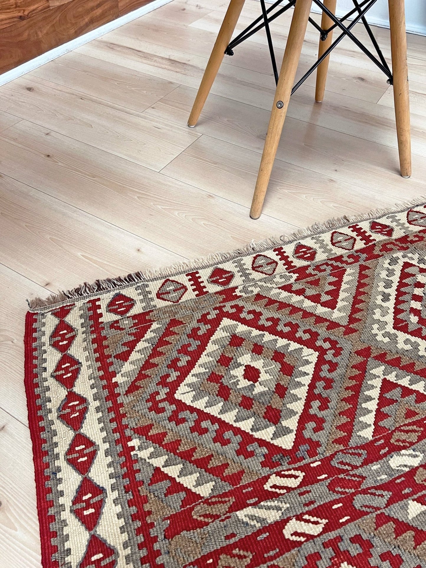 Decorative rug with geometric pattern on a wooden floor. Vintage kurdish van kilim rug 5x8 red beige geometric flatweave eastern anatolia handmade wool tribal rug.