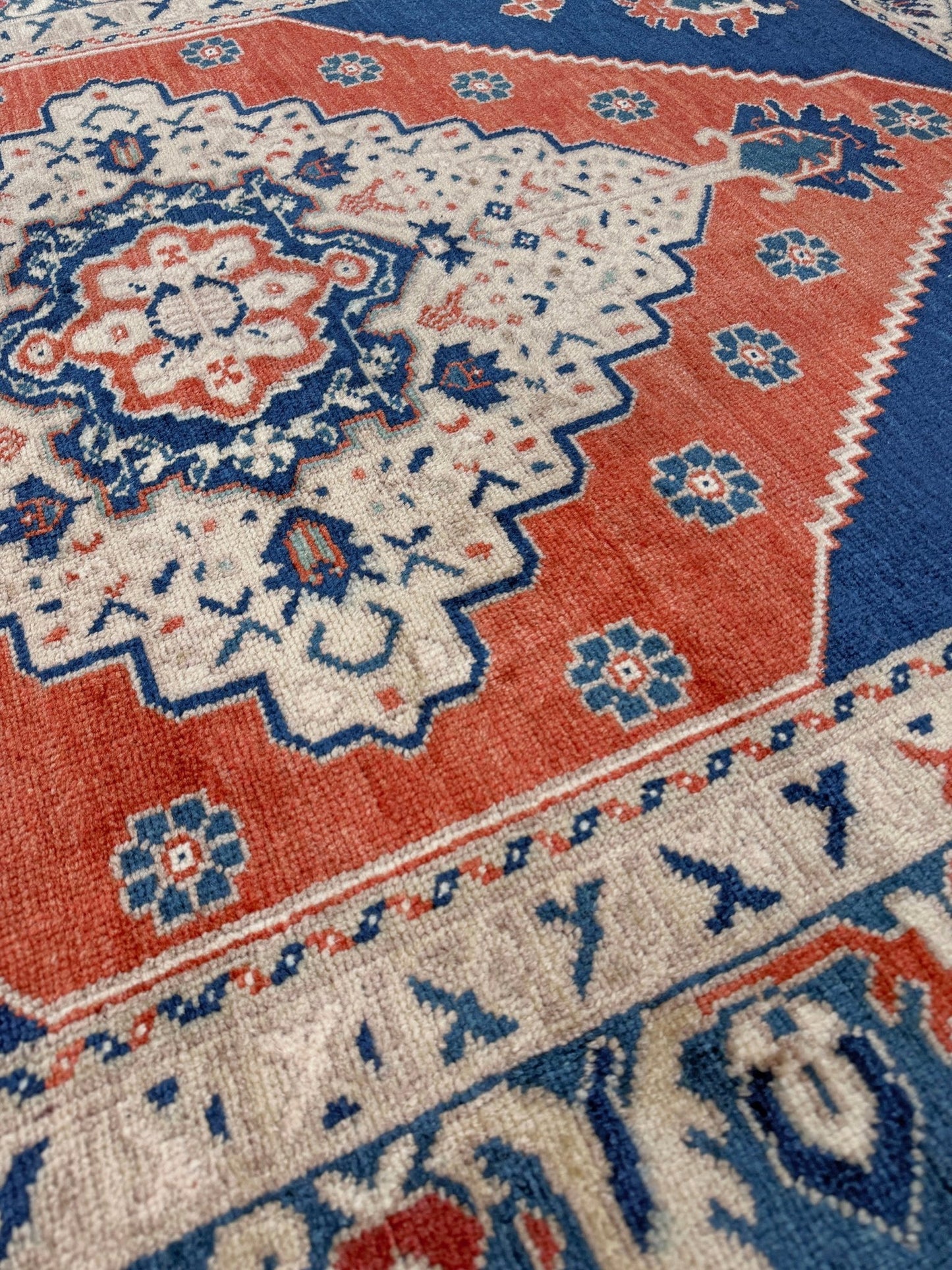 Close-up of a patterned rug with red, blue, and beige colors. Vintage turkish taspinar rug 6x8 indigo blue, salmon red  hand knotted anatolian wool rug pastel san francisco bay area rug shop indigo rugs
