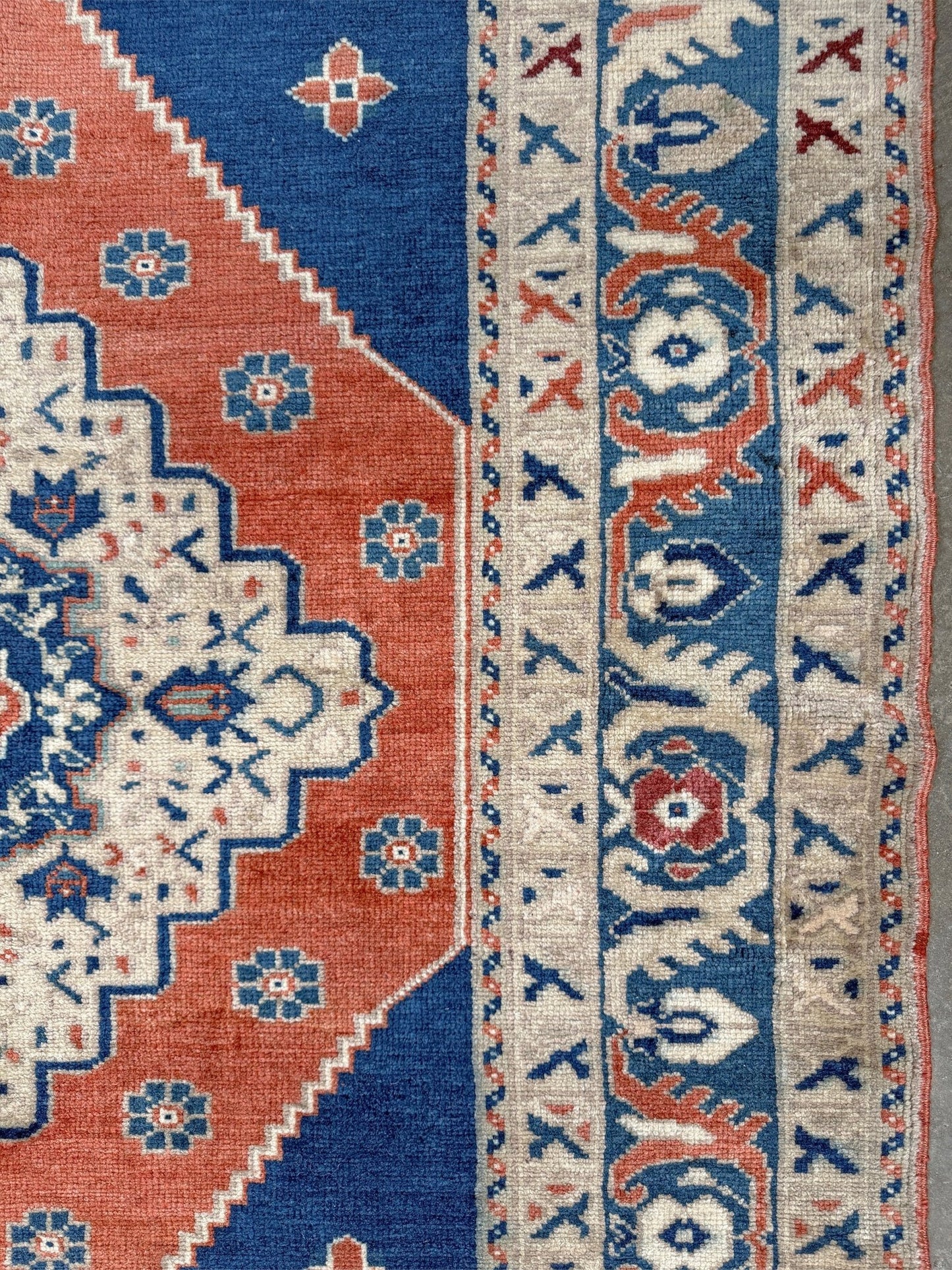 Close-up of a patterned rug with blue, red, and beige colors. Vintage turkish taspinar rug 6x8 indigo blue, salmon red  hand knotted anatolian wool rug pastel san francisco bay area rug shop indigo rugs