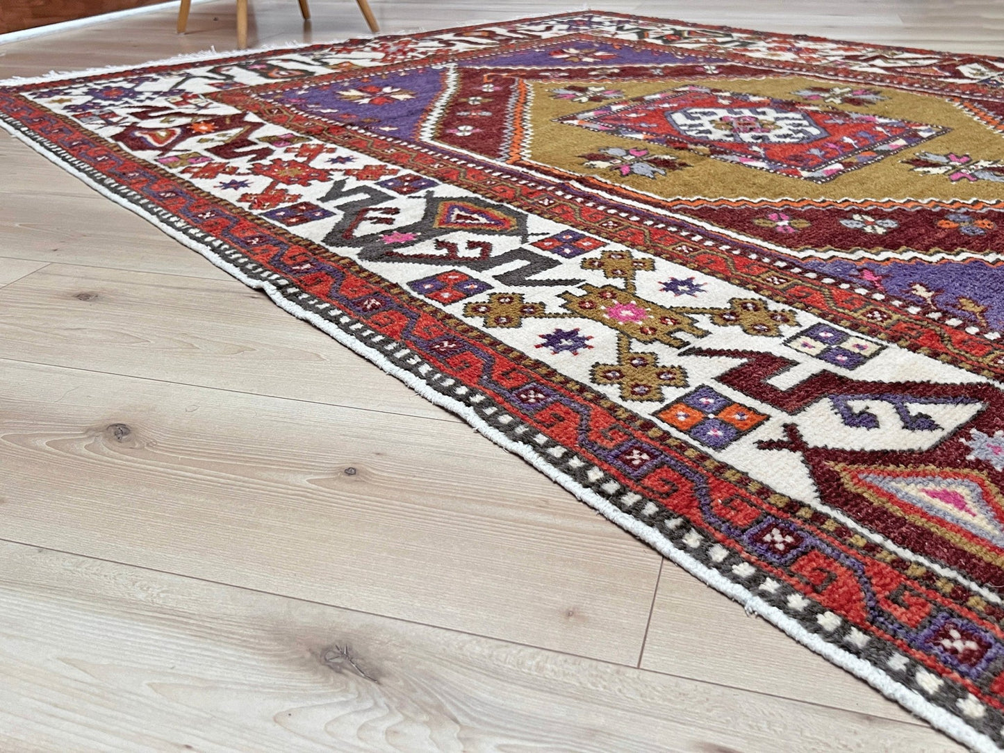 Yuntdag Vintage Turkish Cloudband rug with a golden olive center and bold geometric medallion, surrounded by plum, burgundy, periwinkle, and ivory tribal motifs. Handmade Colorful Vibrant Anatolian wool rug, 6x9 , perfect for living rooms or bedrooms. From Indigo Rugs, Burlingame — San Francisco Bay Area.