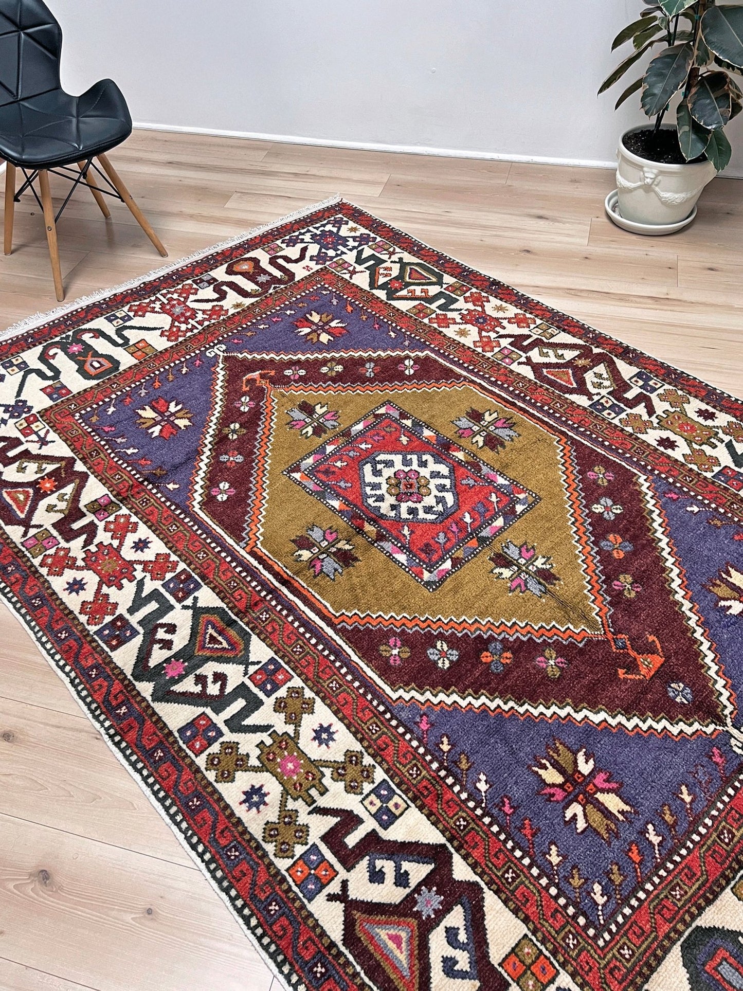 Vintage Turkish Cloudband rug with a golden olive center and bold geometric medallion, surrounded by plum, burgundy, periwinkle, and ivory tribal motifs. Handmade Colorful Vibrant Anatolian wool rug, 6x9 , perfect for living rooms or bedrooms. From Indigo Rugs, Burlingame — San Francisco Bay Area.