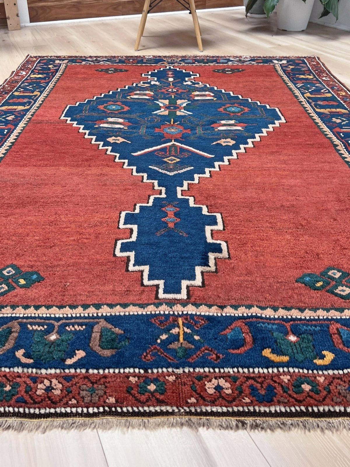 5x7 Vintage Caucasian rug with a terracotta red field and a bold midnight blue geometric medallion. From  the best rug shop san francisco bay area Burlingame CA