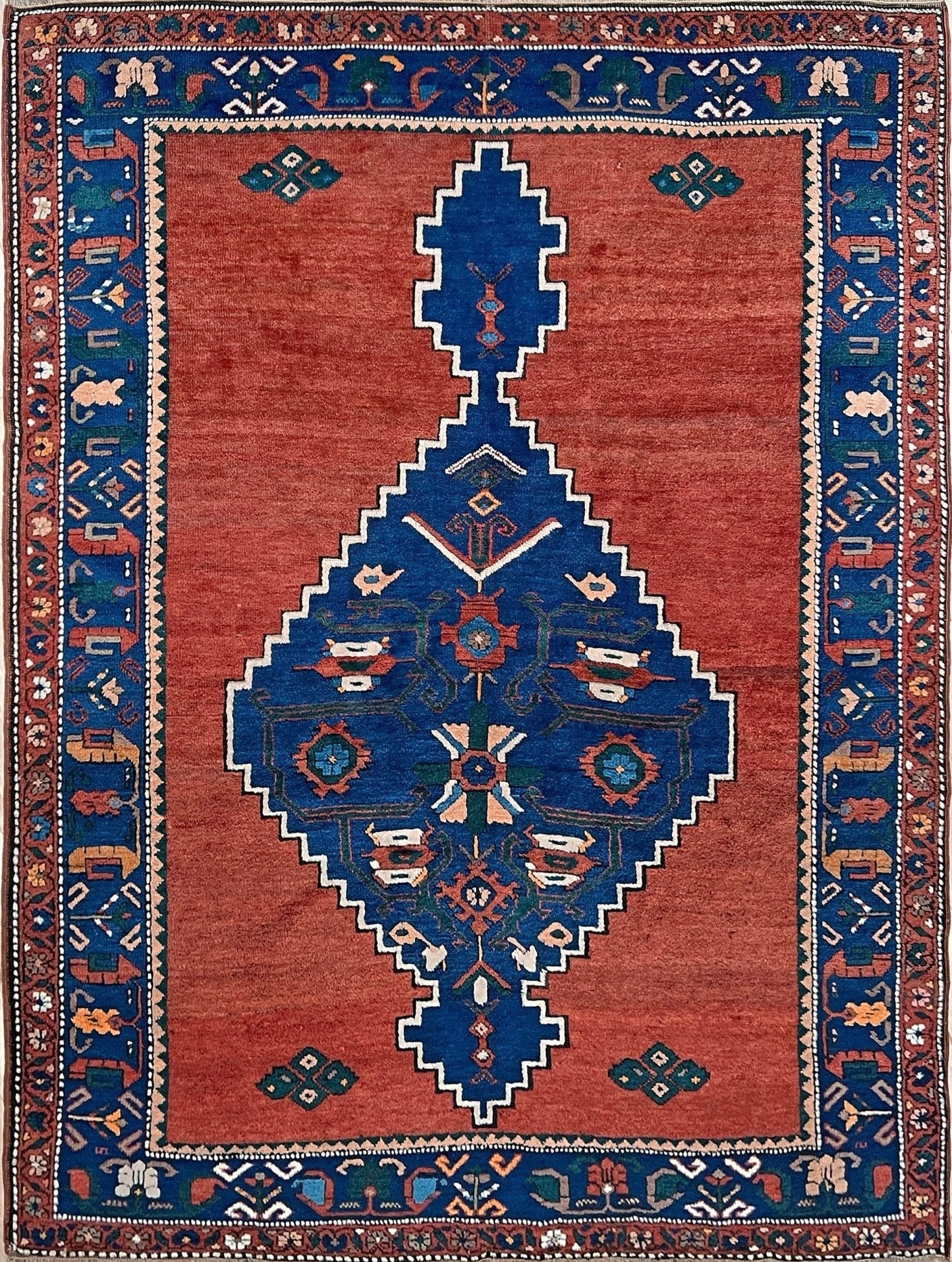 5x7 Vintage Caucasian scatter rug with a terracotta field and a bold midnight blue geometric medallion, accented with melon, ivory, and baby blue motifs. From  the best rug shop san francisco bay area Burlingame CA free shiping