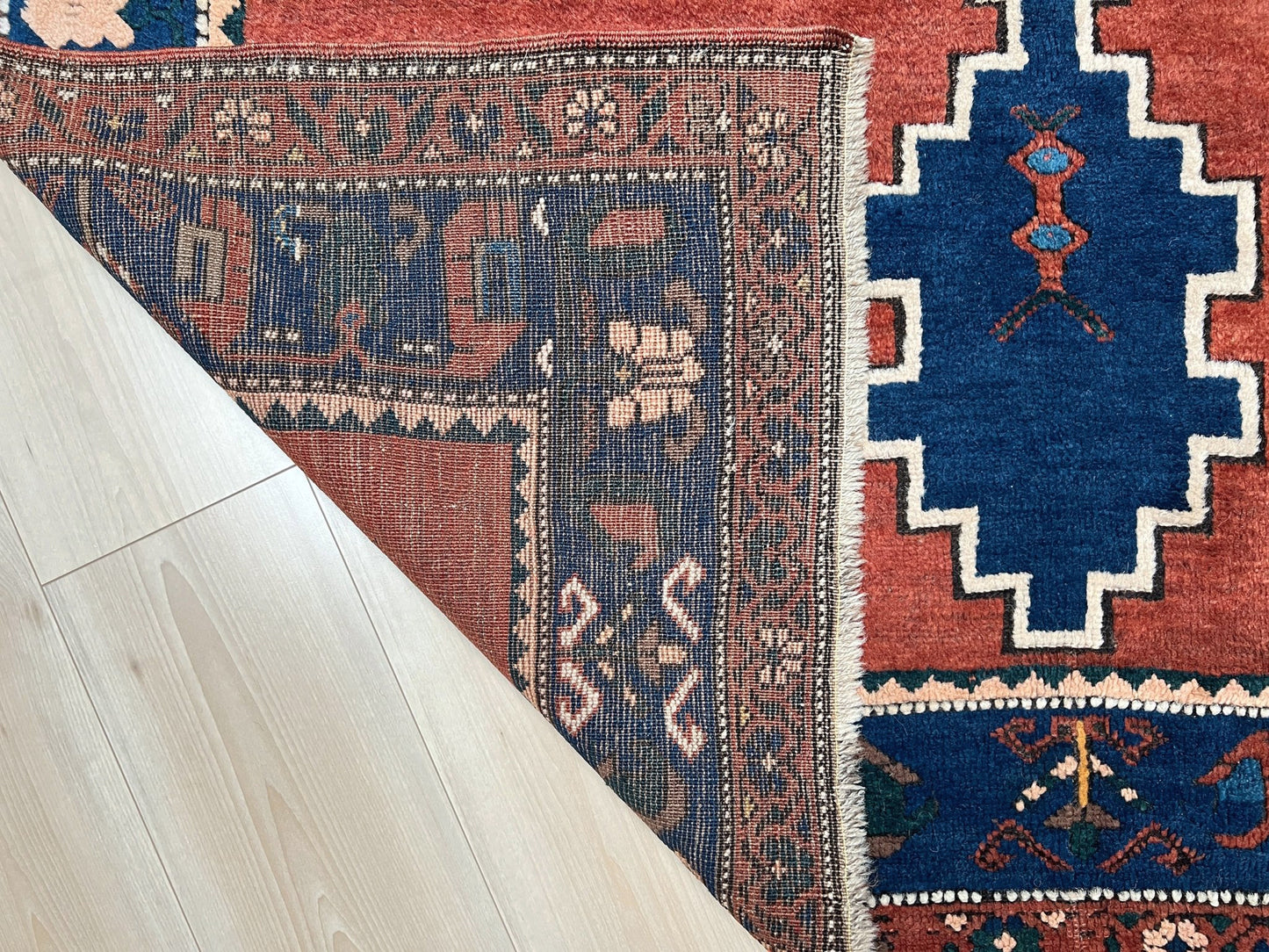 5x7 Vintage Caucasian scatter rug with a terracotta field and a bold midnight blue geometric medallion, accented with melon, ivory, and baby blue motifs. From  the best rug shop san francisco bay area Burlingame CA free shiping