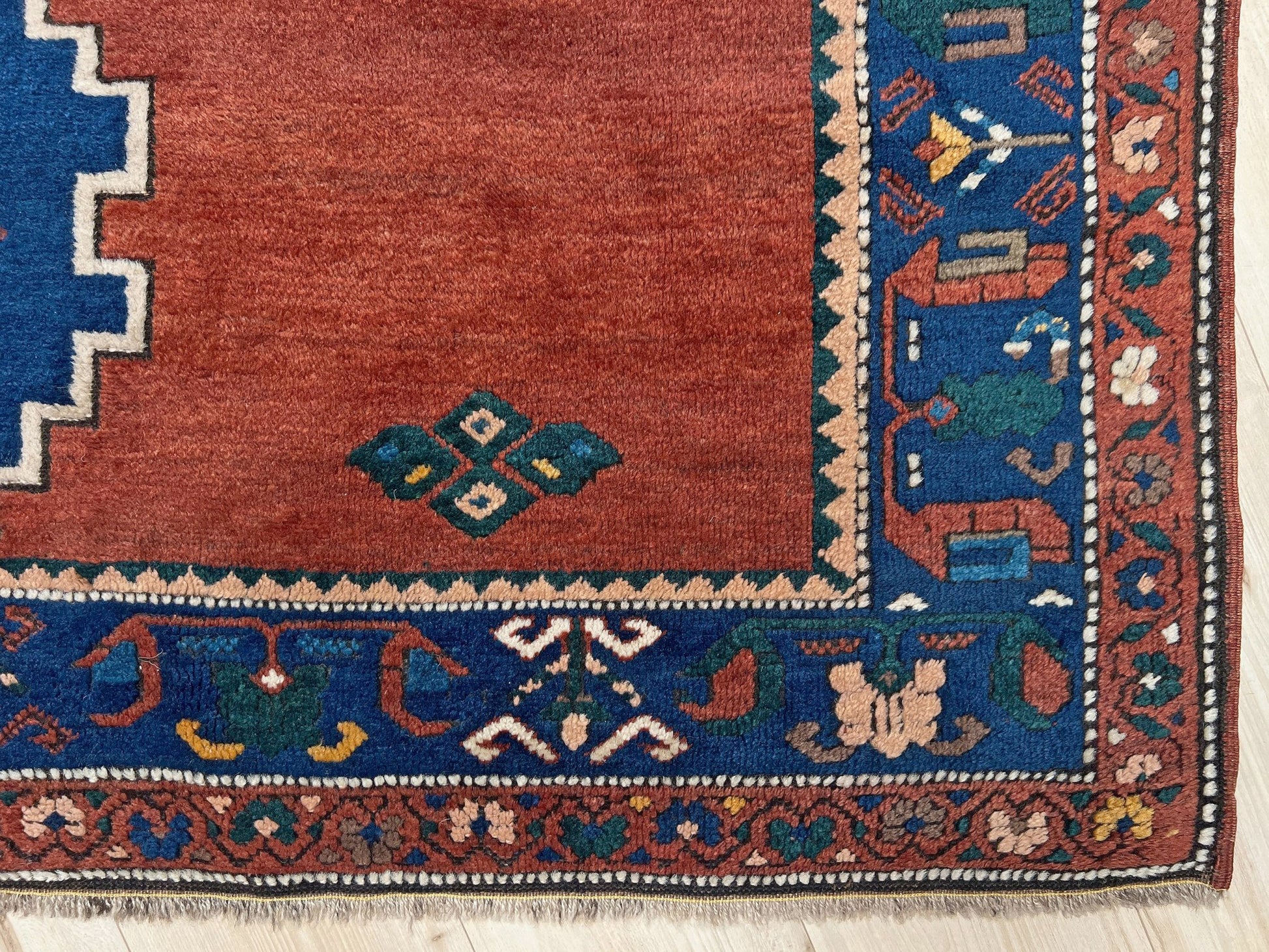 5x7 Vintage Caucasian scatter rug with a terracotta field and a bold midnight blue geometric medallion, accented with melon, ivory, and baby blue motifs. From  the best rug shop san francisco bay area Burlingame CA free shiping