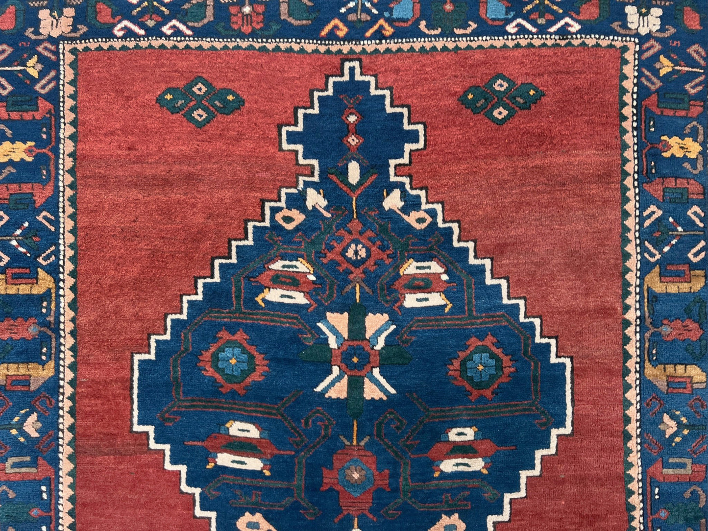 5x7 Vintage Caucasian scatter rug with a terracotta field and a bold midnight blue geometric medallion, accented with melon, ivory, and baby blue motifs. From  the best rug shop san francisco bay area Burlingame CA free shiping