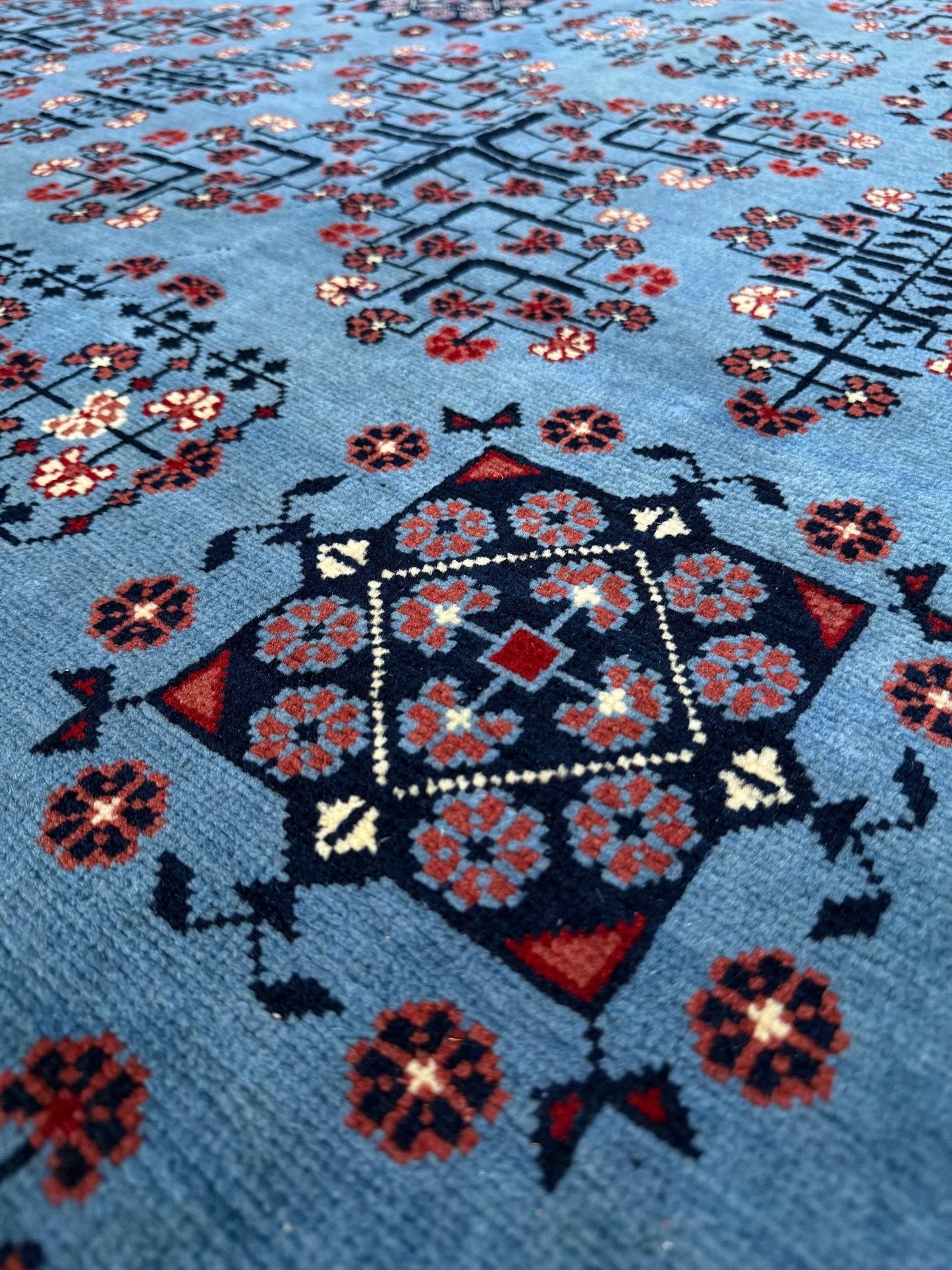 Close-up of 9x12 Handmade Turkmen rug with a baby blue ground, featuring traditional geometric motifs in brown, midnight blue, terracotta crafted from silky Merino wool with a luxurious sheen, available with free shipping from the best handmade rug shop Burlingame CA San Francisco Bay Area.