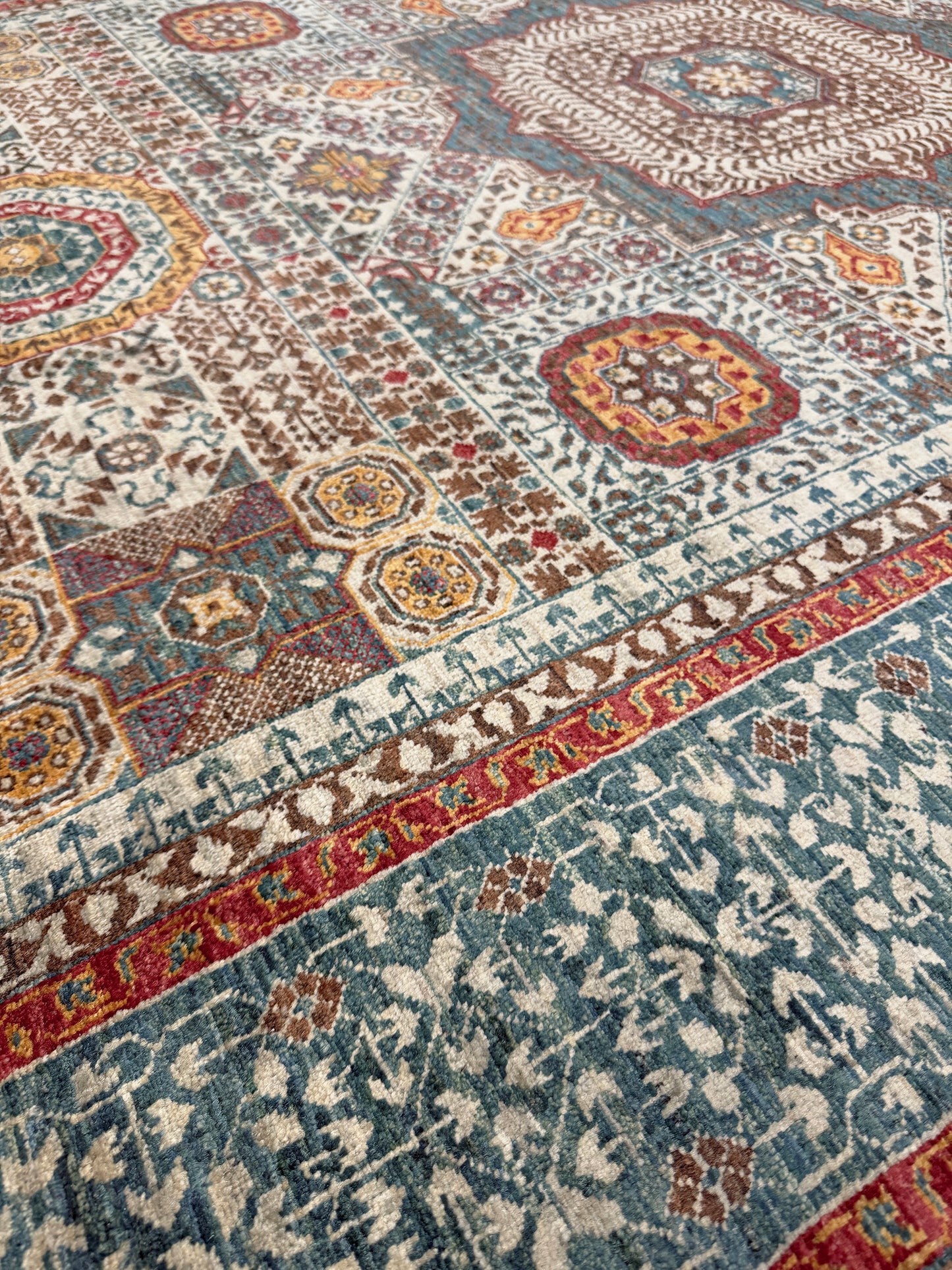Close-up of a patterned rug with multicolor design. dusty teal mamluk transitional handmade wool rug geometric medallion design warm ivory field 5x8 area rug indigo rugs san francisco bay area