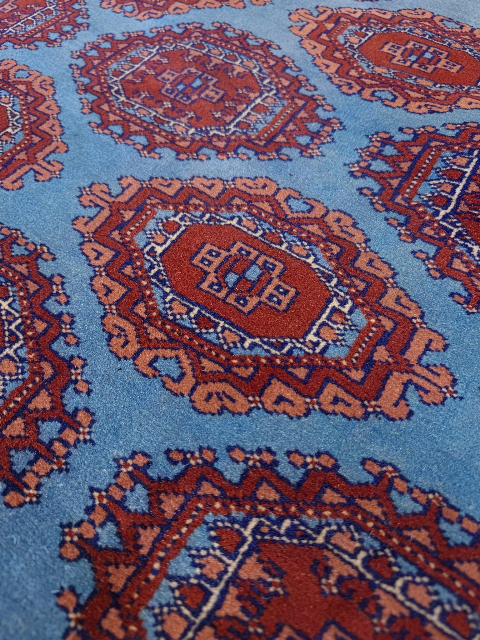Vintage Uzbek Bukhara rug with sky blue field and repeating brick red gul motifs, navy borders, large handmade merino wool area rug 10x14 with velvety pile from Indigo Rugs Burlingame Bay Area