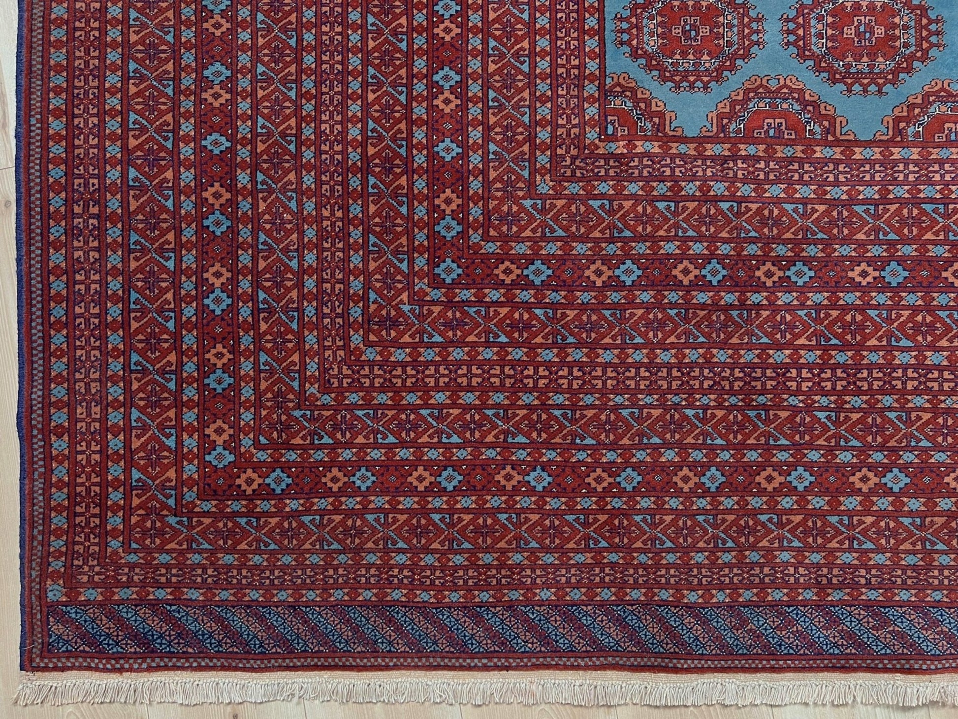 Vintage Uzbek Bukhara rug with sky blue field and repeating brick red gul motifs, navy borders, large handmade merino wool area rug 10x14 with velvety pile from Indigo Rugs Burlingame Bay Area