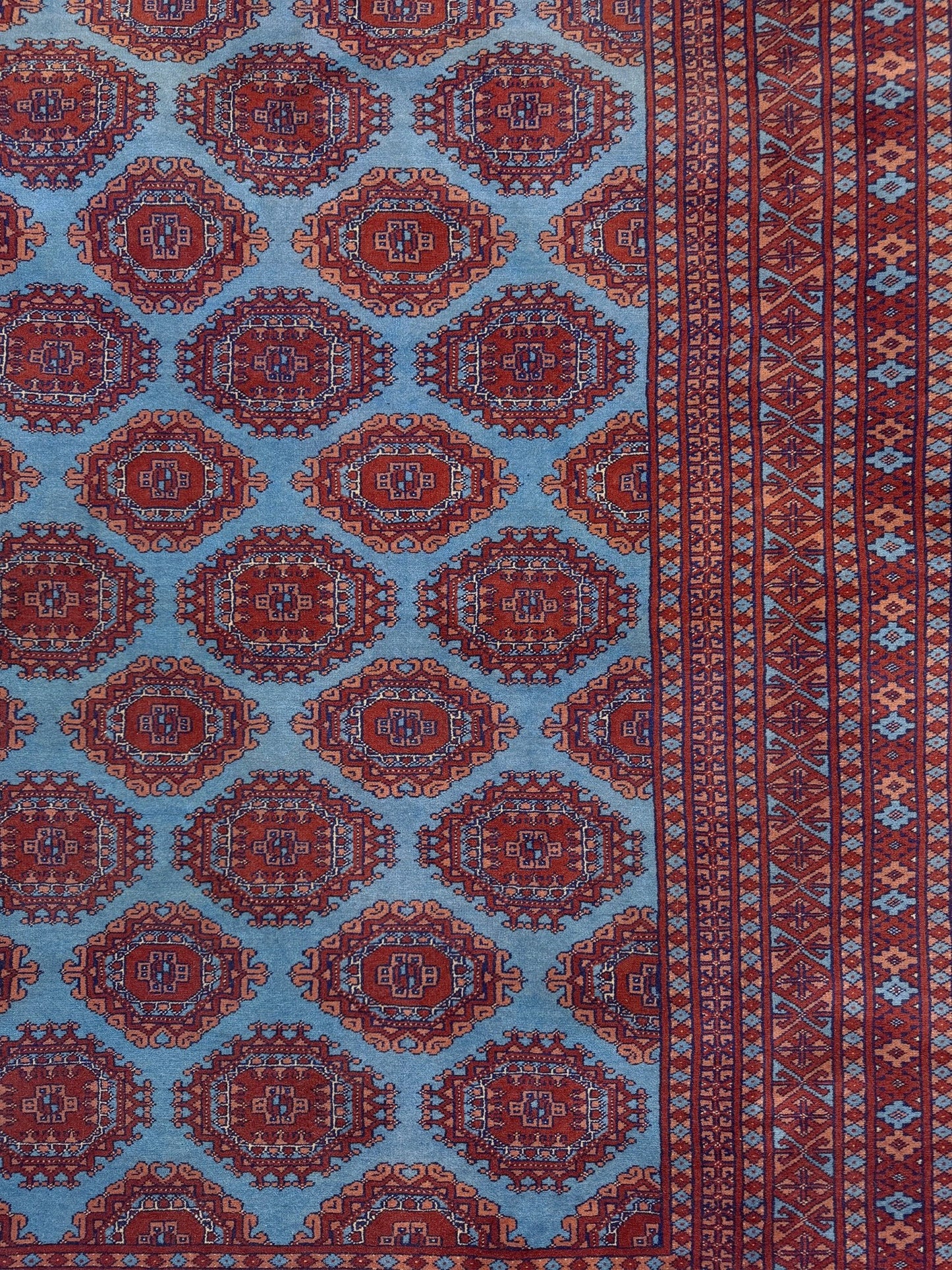 Vintage Uzbek Bukhara rug with sky blue field and repeating brick red gul motifs, navy borders, large handmade merino wool area rug 10x14 with velvety pile from Indigo Rugs Burlingame Bay Area