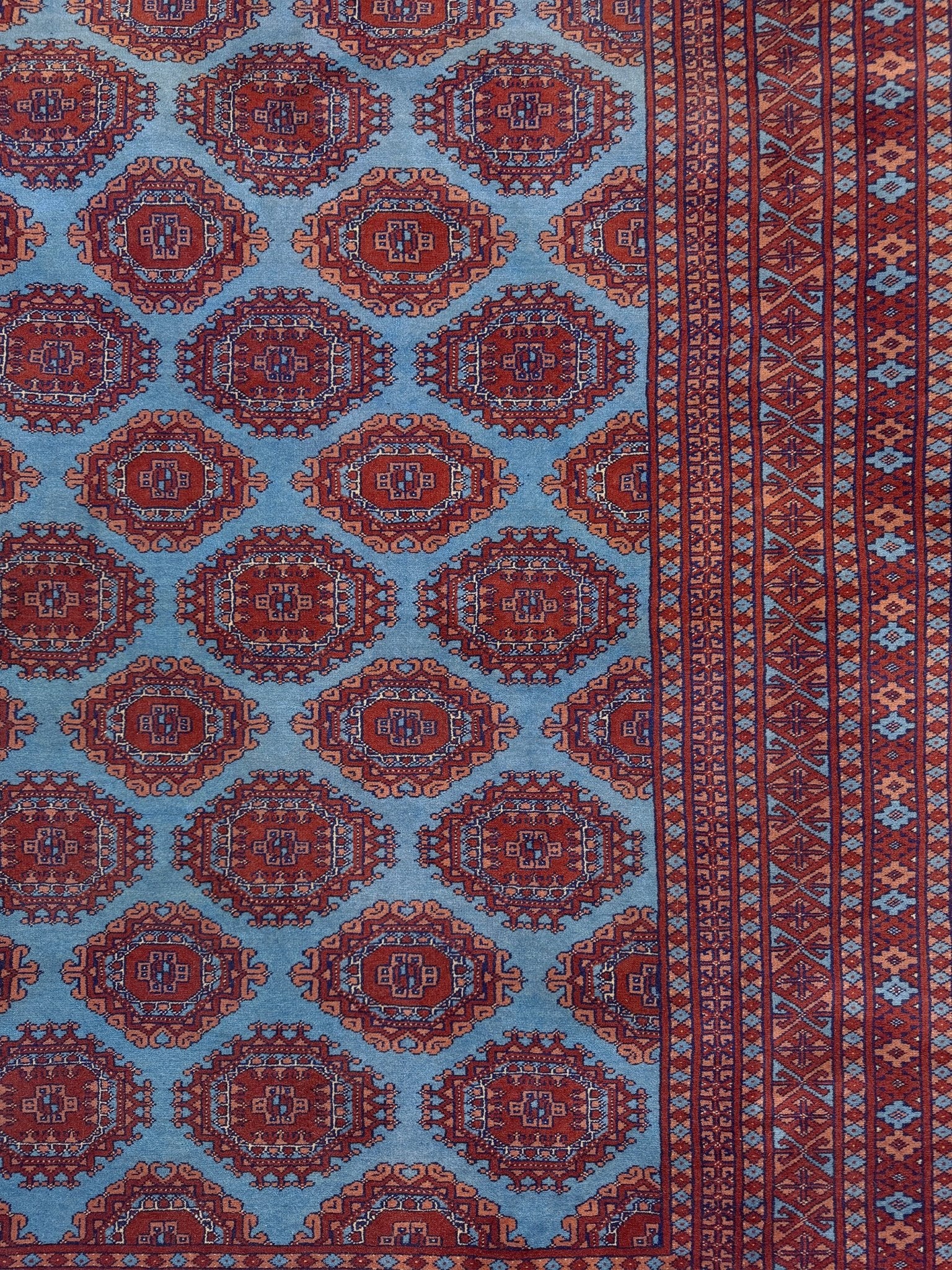 Vintage Uzbek Bukhara rug with sky blue field and repeating brick red gul motifs, navy borders, large handmade merino wool area rug 10x14 with velvety pile from Indigo Rugs Burlingame Bay Area