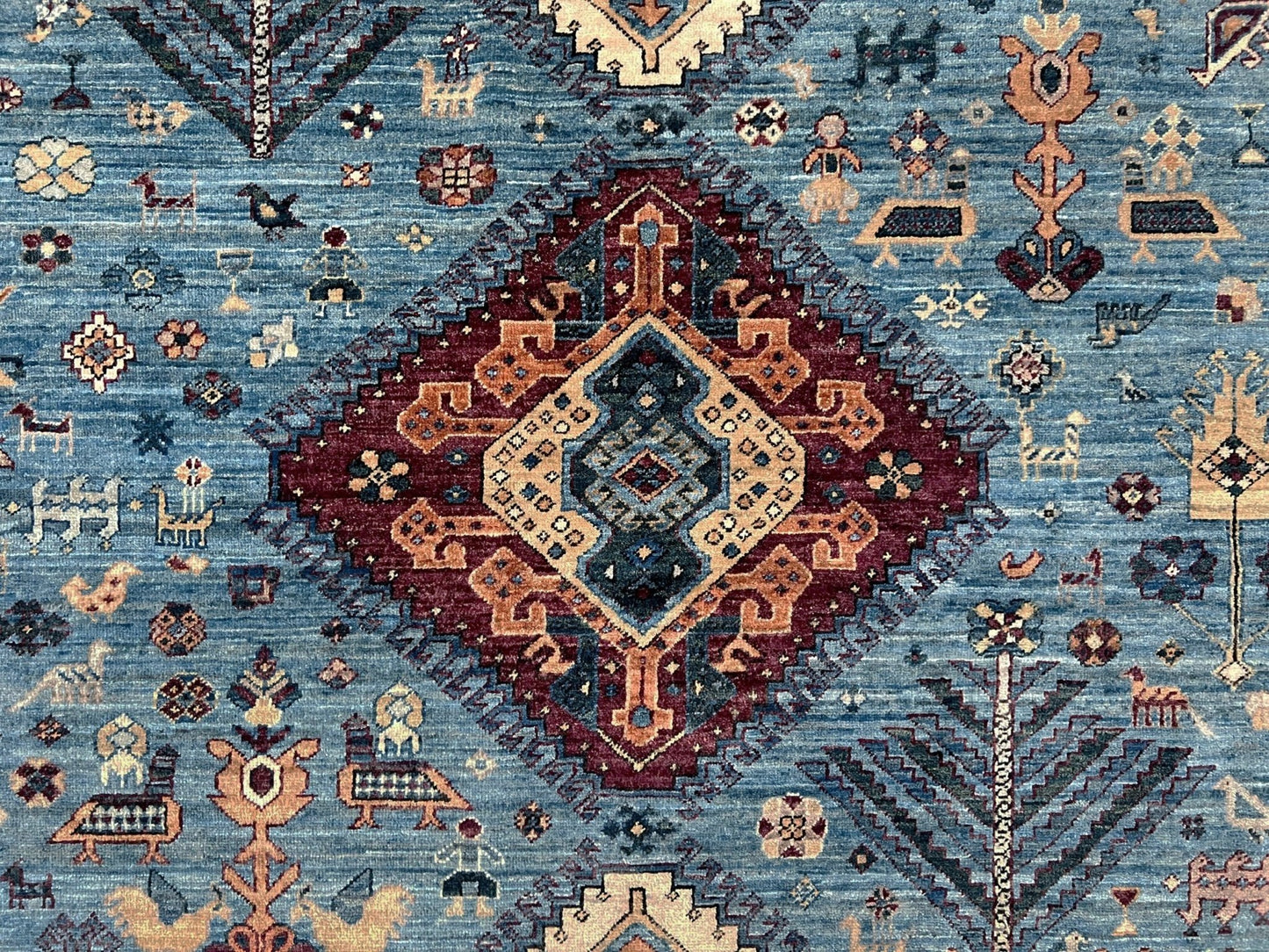 Decorative rug with intricate patterns and colors on a blue background. large handmade sky blue and deep maroon turkish rug 9x12 geometric medallion design transitional tribal wool rug soft pile indigo rugs burlingame san francisco bay area