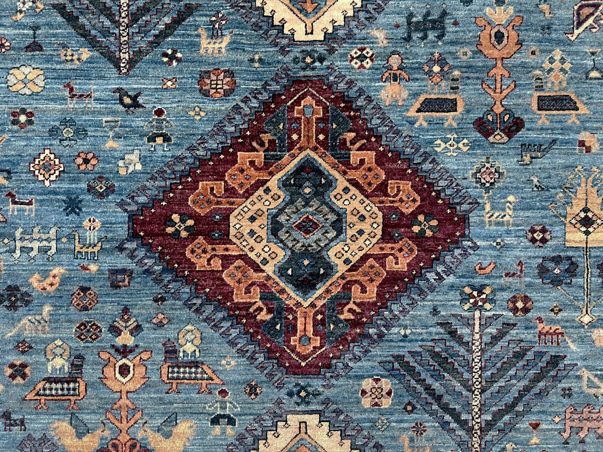 Decorative rug with intricate patterns and colors on a blue background. large handmade sky blue and deep maroon turkish rug 9x12 geometric medallion design transitional tribal wool rug soft pile indigo rugs burlingame san francisco bay area