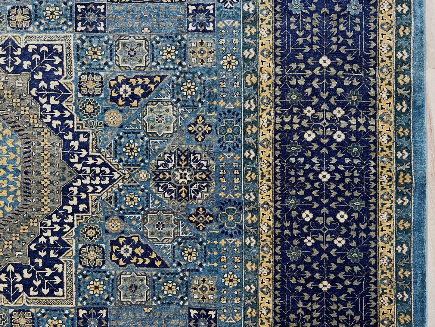 Decorative blue and gold rug with intricate patterns on a wooden floor. Brand new fine Mamluk rug 10x14 with navy, denim blue, and soft gold geometric medallion design, high knot density (50×50 ~156 KPSI), perfect for large living rooms and dining spaces. From Indigo Rugs, Burlingame — the best rug shop in the San Francisco Bay Area. Free shipping.