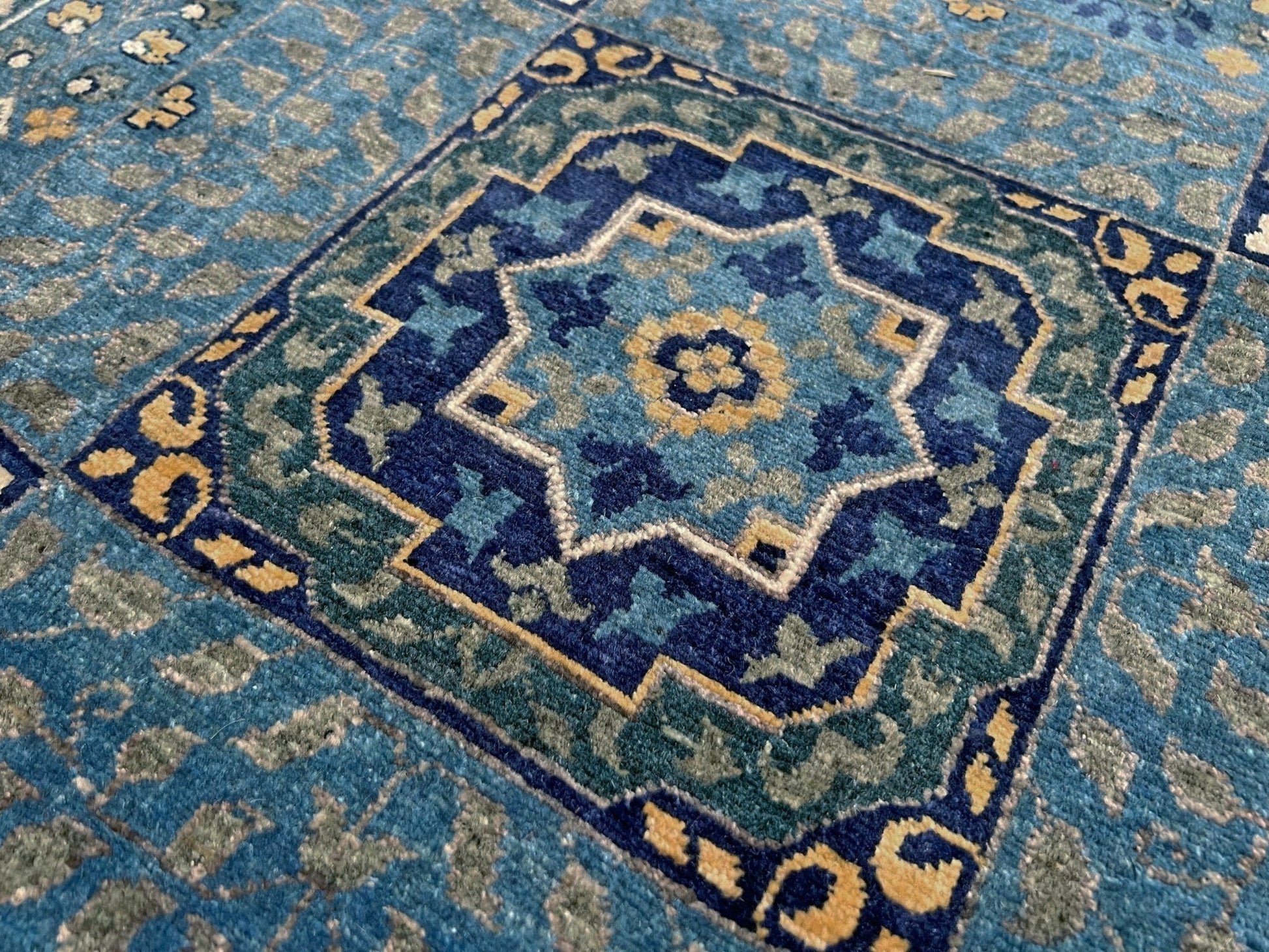 Decorative blue and gold rug with intricate patterns on a wooden floor. Brand new fine Mamluk rug 10x14 with navy, denim blue, and soft gold geometric medallion design, high knot density (50×50 ~156 KPSI), perfect for large living rooms and dining spaces. From Indigo Rugs, Burlingame — the best rug shop in the San Francisco Bay Area. Free shipping.