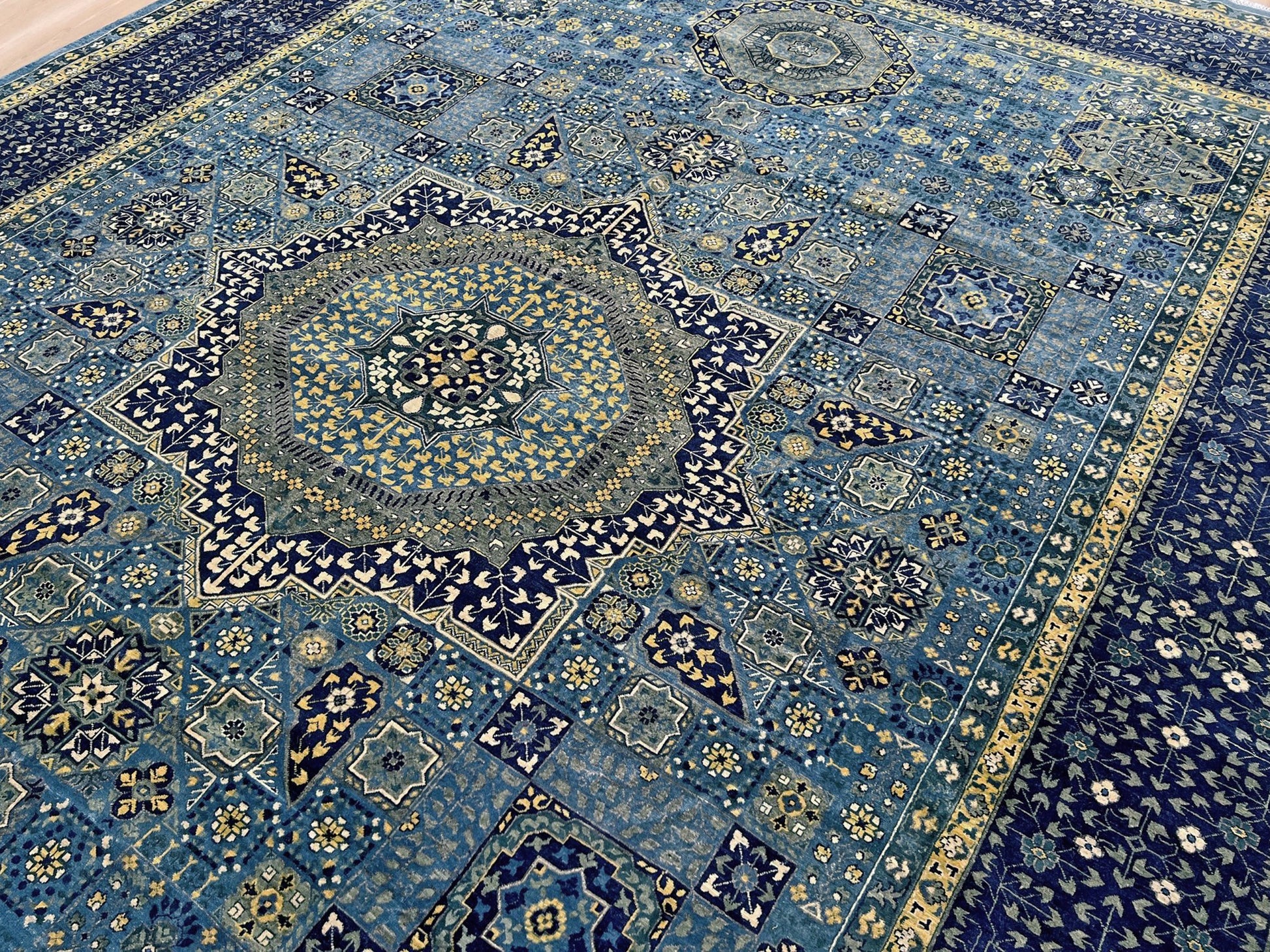 Close-up of a Decorative blue rug with intricate patterns. Brand new fine Mamluk rug 10x14 with navy, denim blue, and soft gold geometric medallion design, high knot density (50×50 ~156 KPSI), perfect for large living rooms and dining spaces. From Indigo Rugs, Burlingame — the best rug shop in the San Francisco Bay Area. Free shipping.