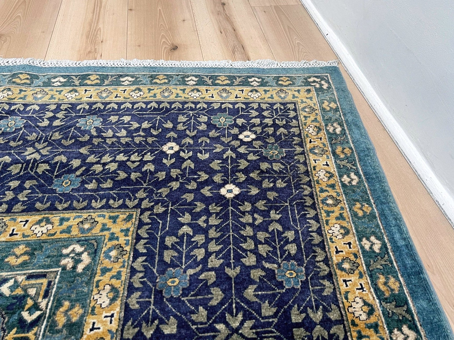Decorative blue and gold rug with intricate patterns on a wooden floor. Brand new fine Mamluk rug 10x14 with navy, denim blue, and soft gold geometric medallion design, high knot density (50×50 ~156 KPSI), perfect for large living rooms and dining spaces. From Indigo Rugs, Burlingame — the best rug shop in the San Francisco Bay Area. Free shipping.
