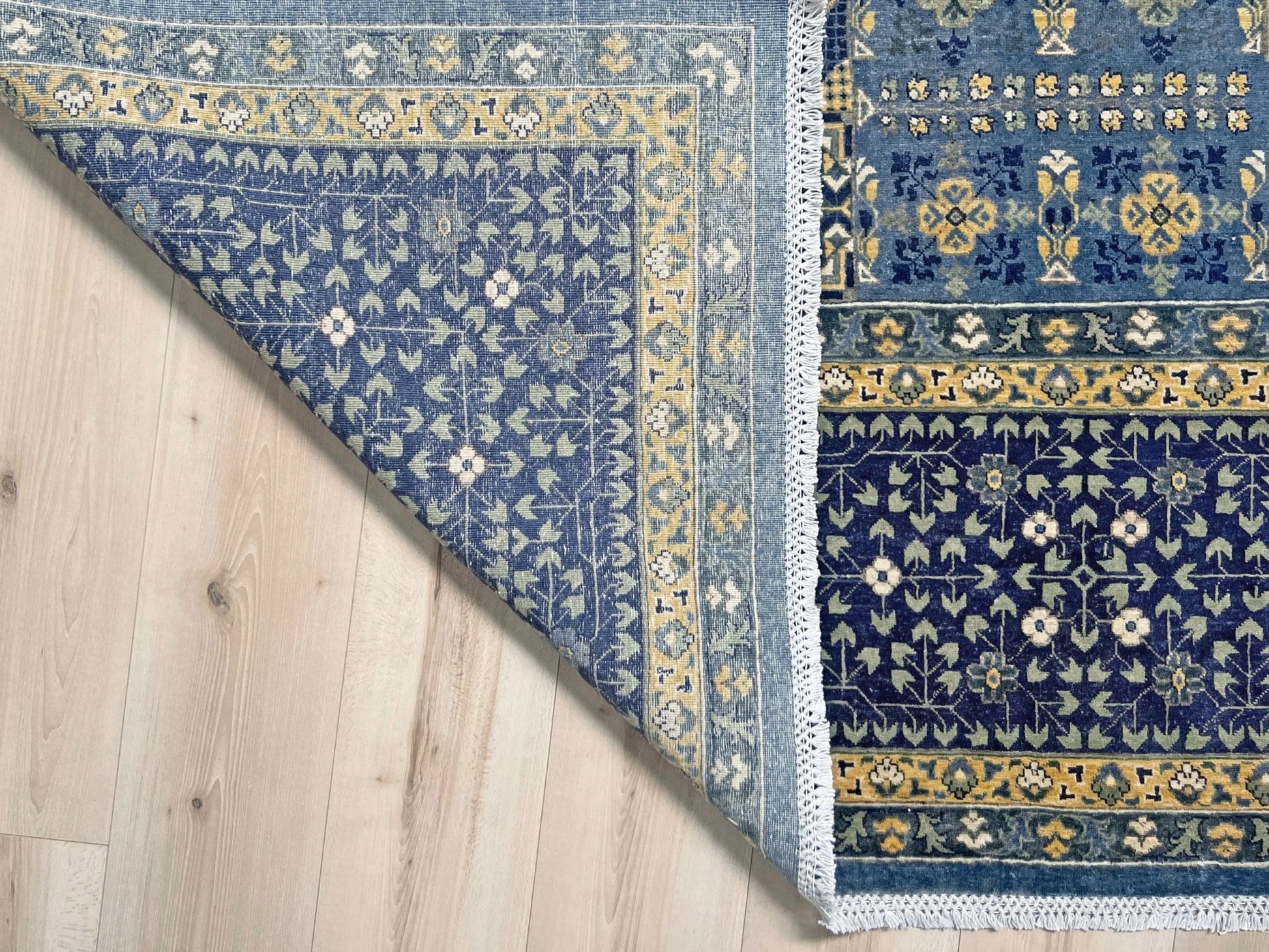 Decorative blue and gold rug with intricate patterns on a wooden floor. Brand new fine Mamluk rug 10x14 with navy, denim blue, and soft gold geometric medallion design, high knot density (50×50 ~156 KPSI), perfect for large living rooms and dining spaces. From Indigo Rugs, Burlingame — the best rug shop in the San Francisco Bay Area. Free shipping.