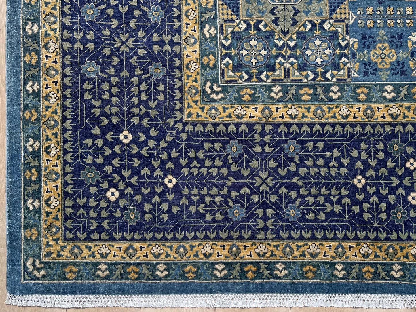 Decorative blue and gold rug with intricate patterns on a wooden floor. Brand new fine Mamluk rug 10x14 with navy, denim blue, and soft gold geometric medallion design, high knot density (50×50 ~156 KPSI), perfect for large living rooms and dining spaces. From Indigo Rugs, Burlingame — the best rug shop in the San Francisco Bay Area. Free shipping.