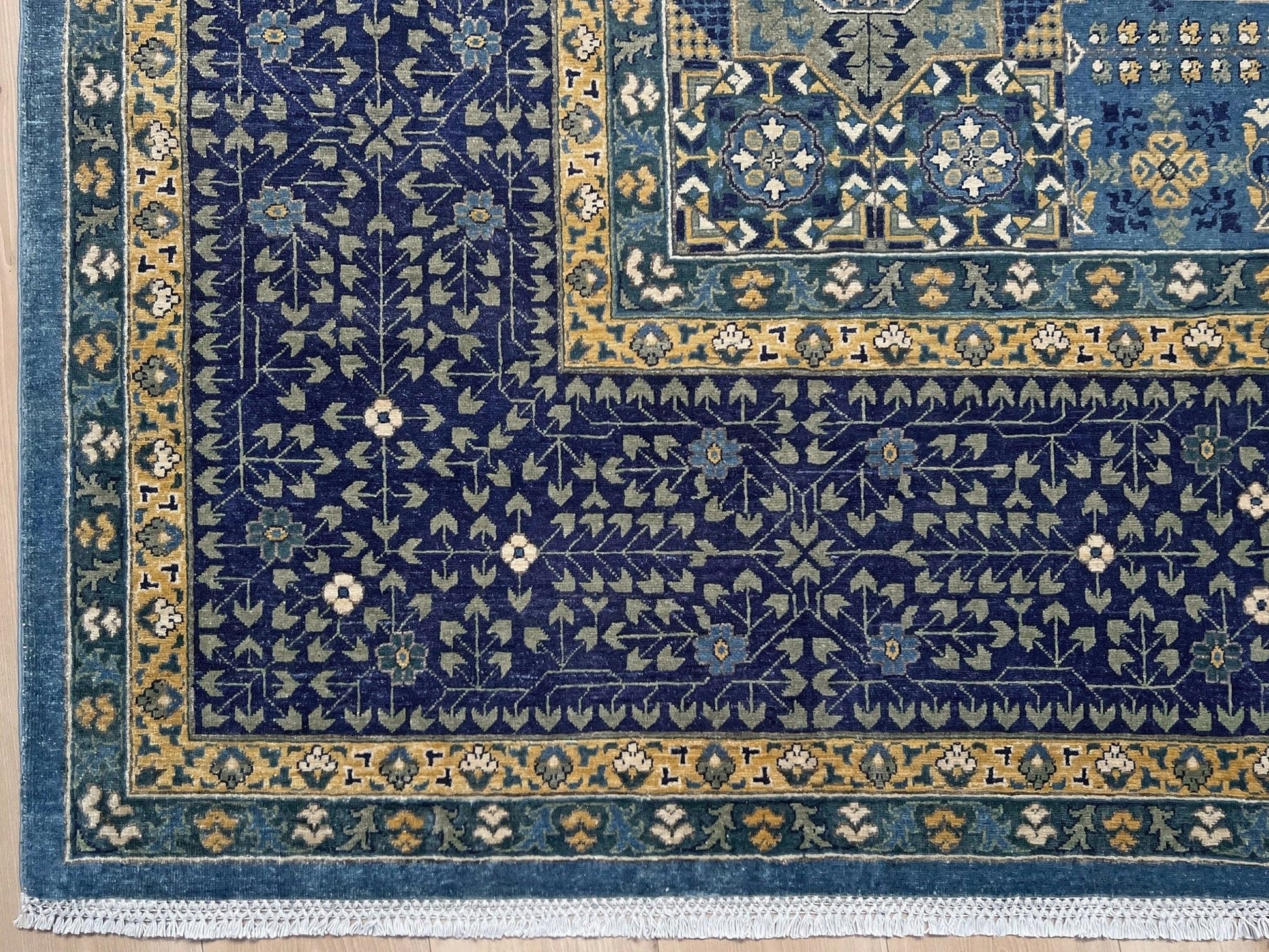 Decorative blue and gold rug with intricate patterns on a wooden floor. Brand new fine Mamluk rug 10x14 with navy, denim blue, and soft gold geometric medallion design, high knot density (50×50 ~156 KPSI), perfect for large living rooms and dining spaces. From Indigo Rugs, Burlingame — the best rug shop in the San Francisco Bay Area. Free shipping.