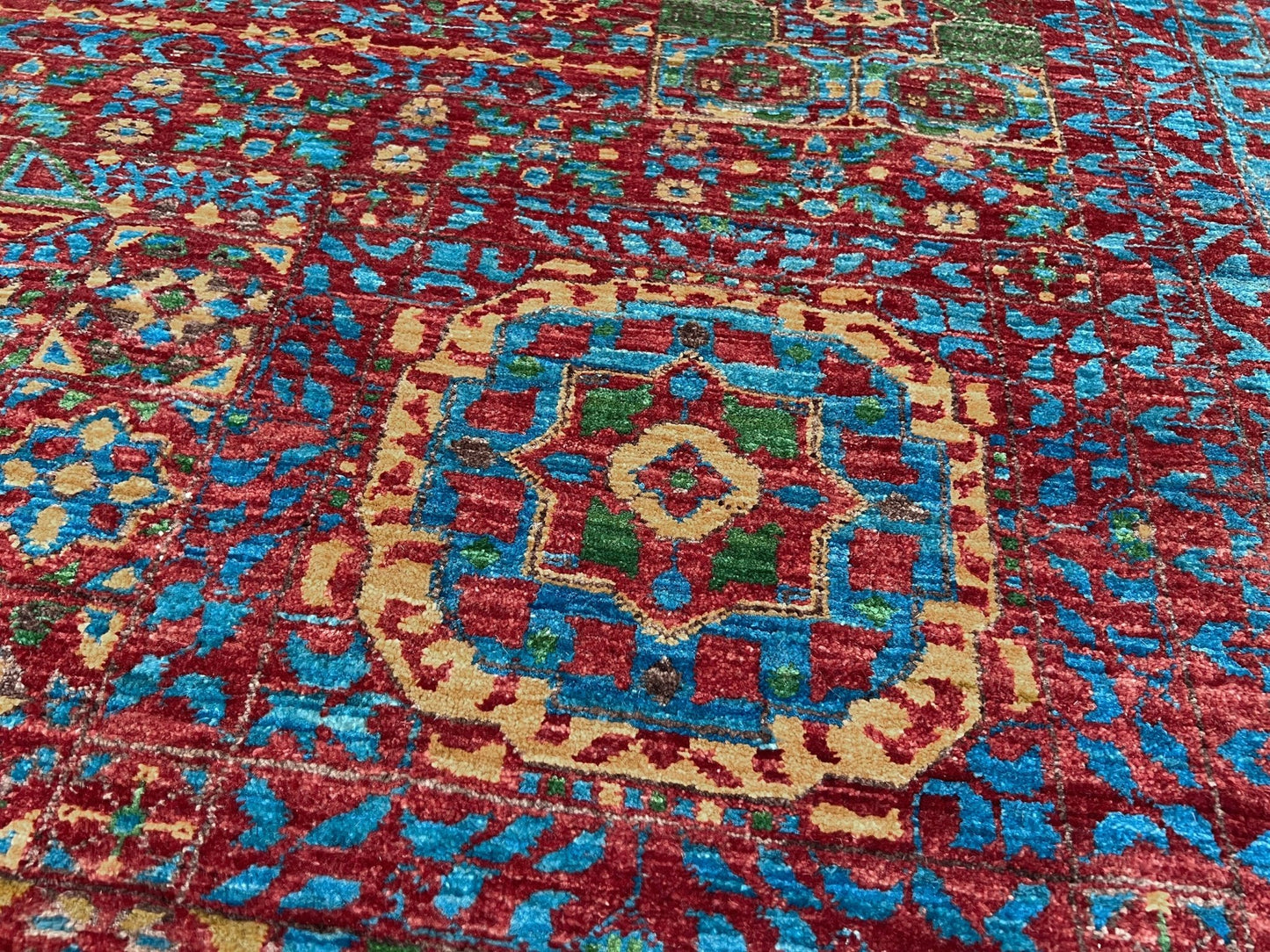 Regal Mamluk area rug made from luxurious Ghazni wool, featuring a rich color combination of deep reds, blues, golds, and greens. This handmade carpet showcases intricate geometric patterns and medallions, adding elegance and sophistication to any living room, bedroom, dining area, or office. Available from the best rug shop in the San Francisco Bay Area, this luxury rug comes with free shipping across the U.S.