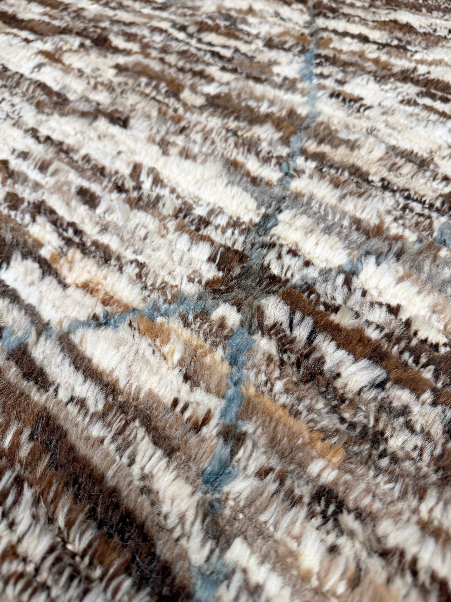 Close-up of a textured fabric with brown, beige, and blue pattern. Square 9x10 handmade Turkish Tulu rug with ivory and brown textured wool pile, subtle diamond lattice design — shown at Indigo Rugs, Burlingame — San Francisco Bay Area with free shipping