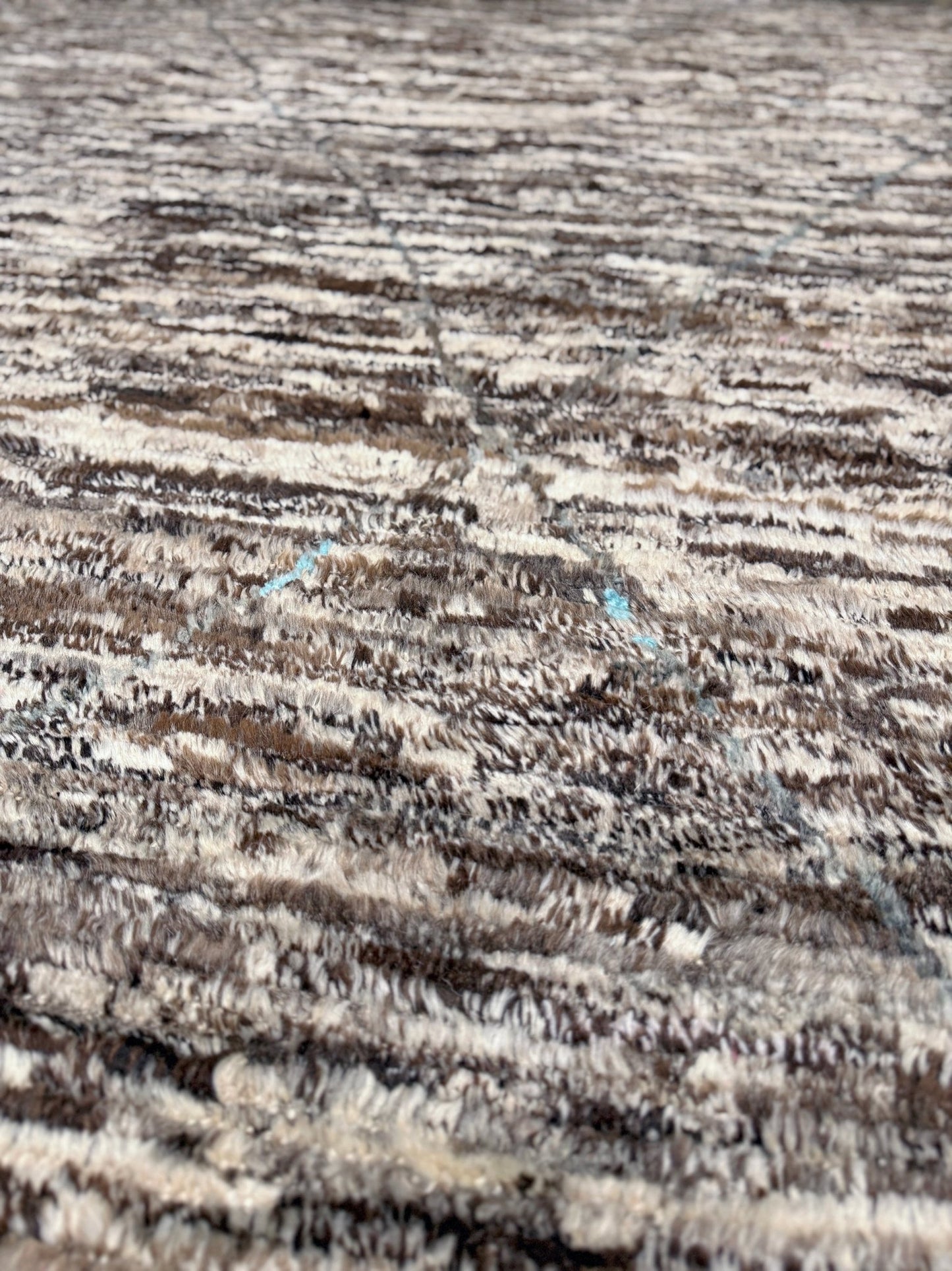 Close-up of textured fabric with a pattern of lines and dots. Square 9x10 handmade Turkish Tulu rug with ivory and brown textured wool pile, subtle diamond lattice design — shown at Indigo Rugs, Burlingame — San Francisco Bay Area with free shipping