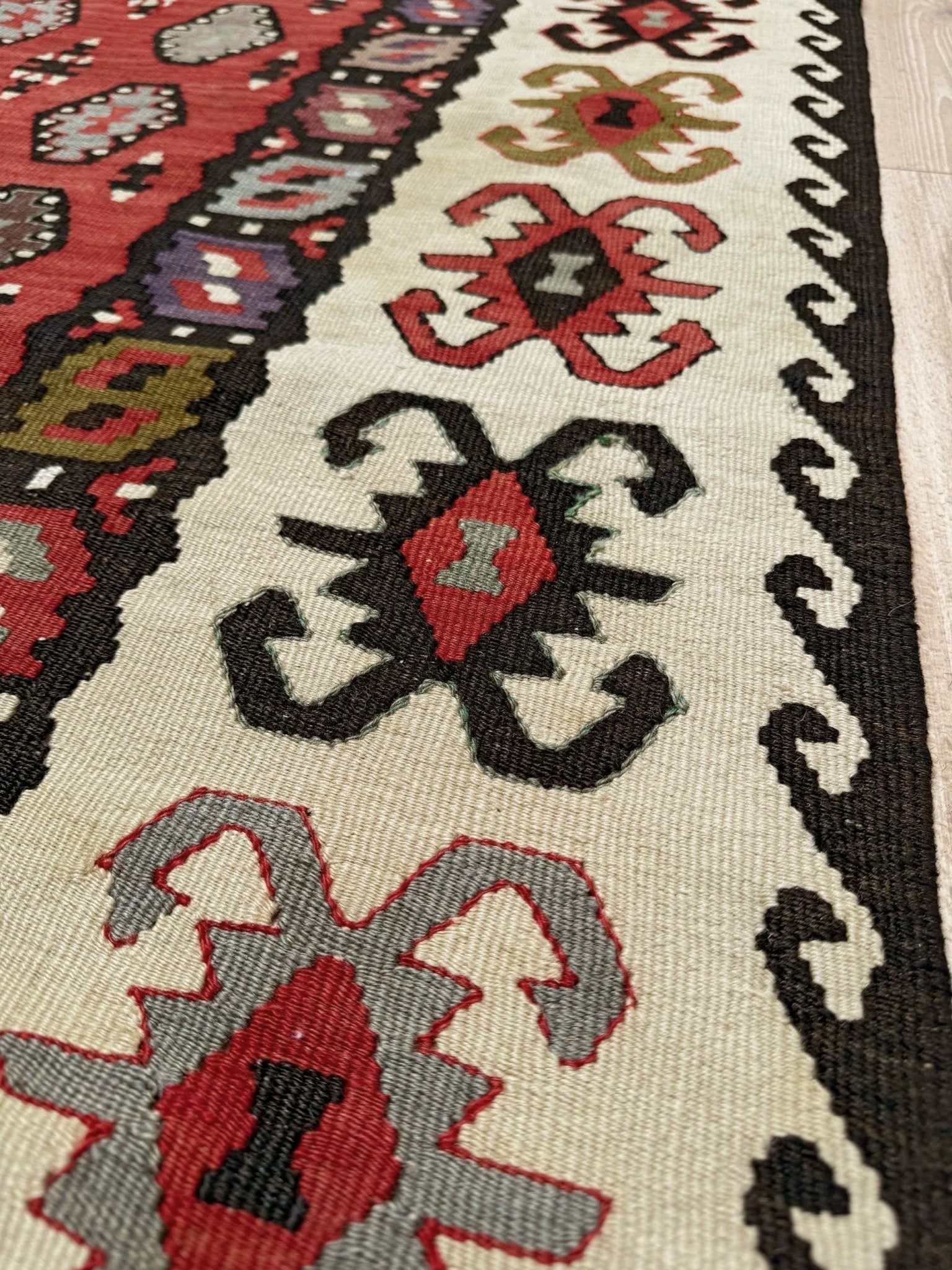 Decorative rug with intricate pattern on a red background. Vintage Pirot kilim with warm madder red field and repeating geometric medallions, handwoven wool flatweave rug with ivory border, approx. 7x10.