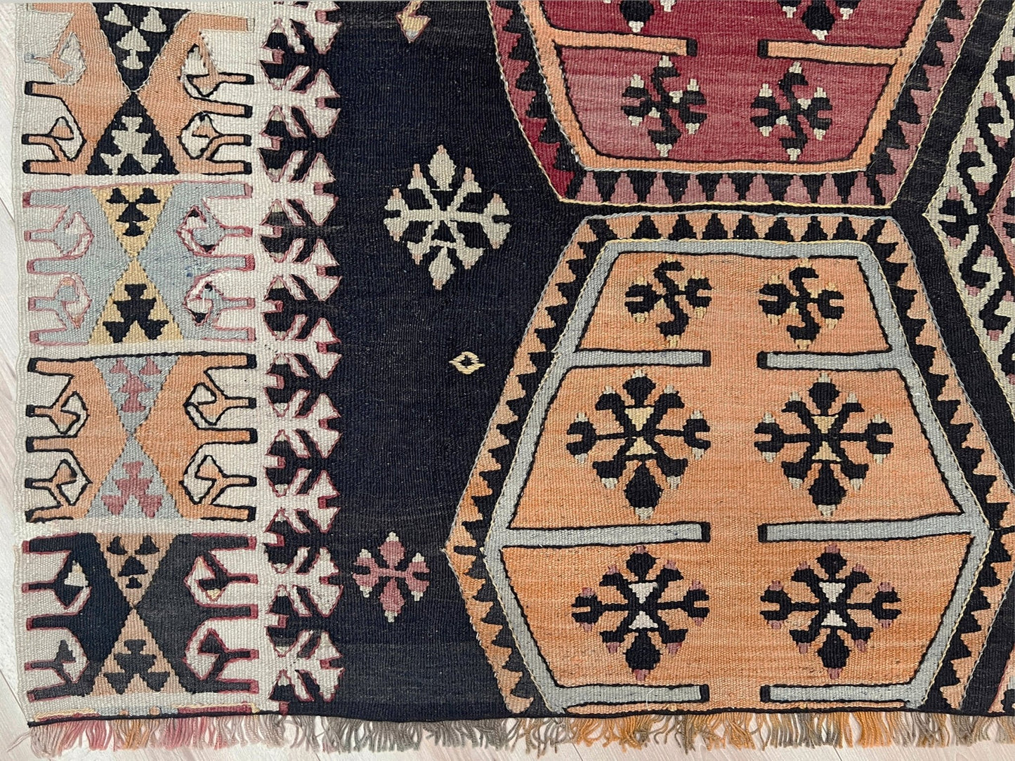 Close-up of a patterned rug with geometric designs in various colors. Vintage Sarkisla Turkish kilim rug 6x9 with deep brown field and geometric medallions in madder red, camel, and ivory tones — handmade Anatolian flatweave carpet