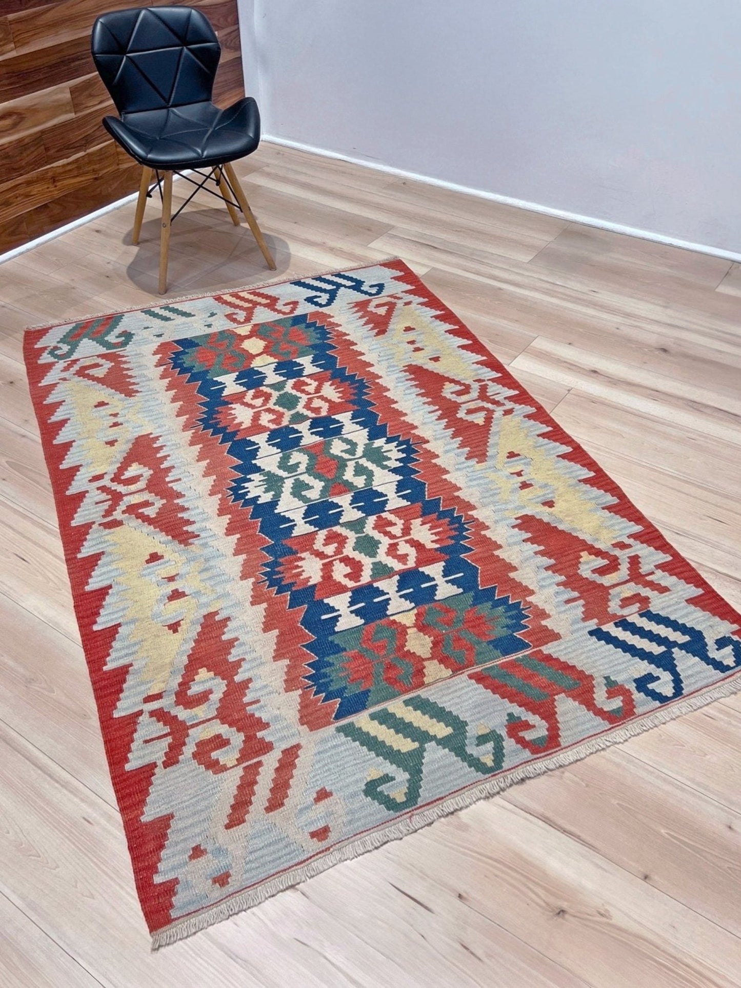 Woven turkish kilim rug with geometric pattern featuring red, blue, and beige colors. 
