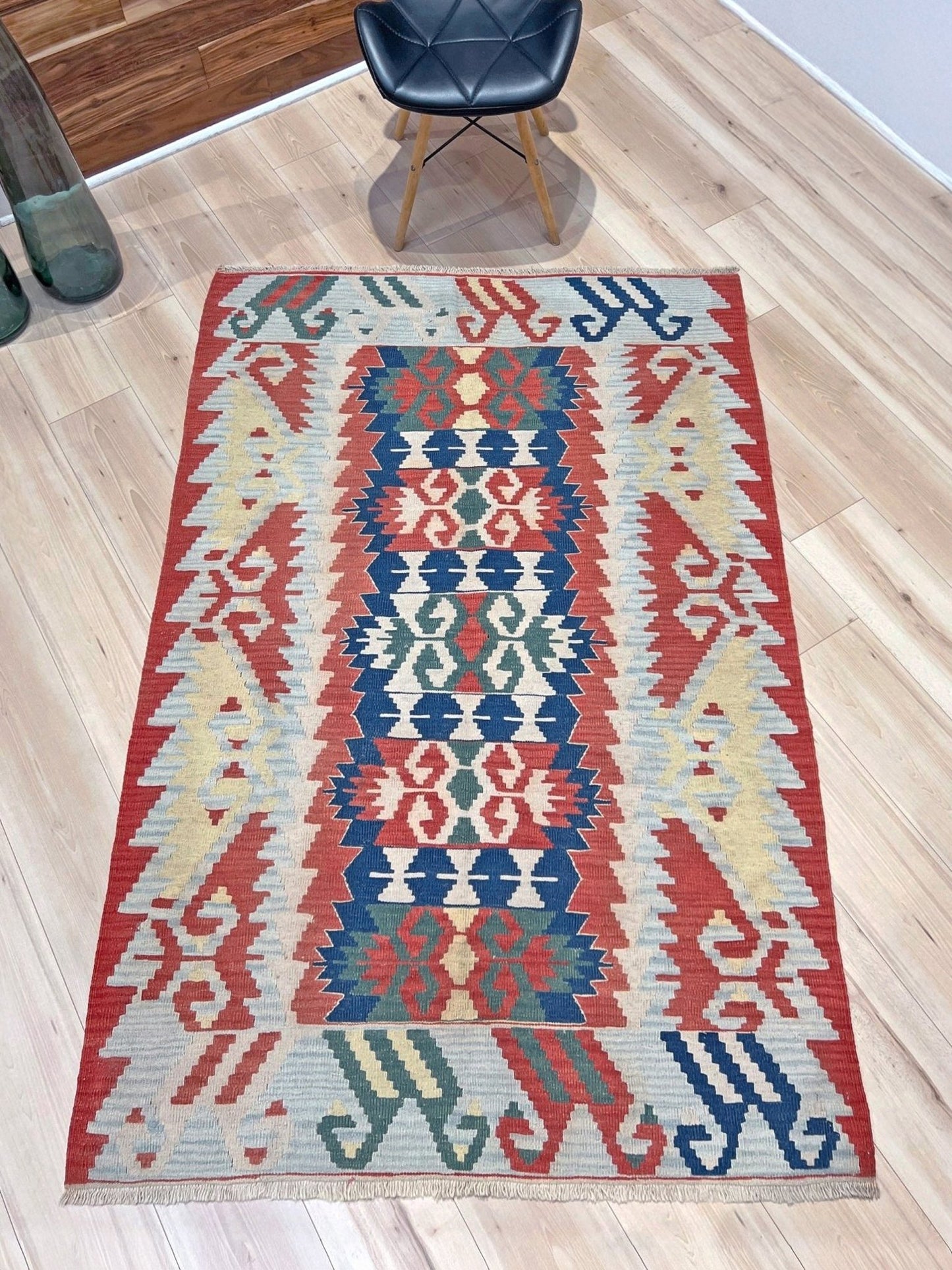 Woven turkish kilim rug with geometric pattern featuring red, blue, and beige colors. 