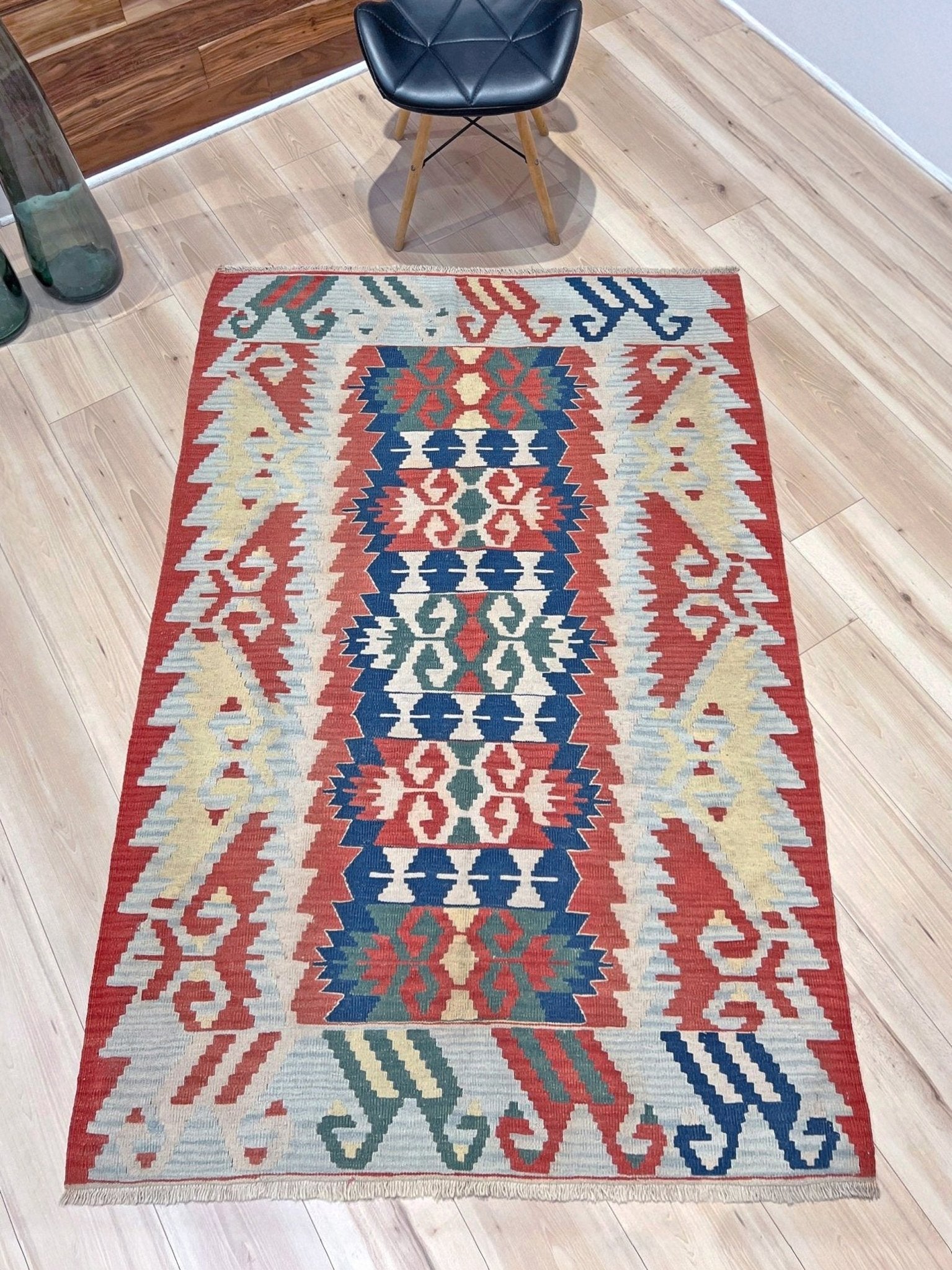 Woven turkish kilim rug with geometric pattern featuring red, blue, and beige colors. 