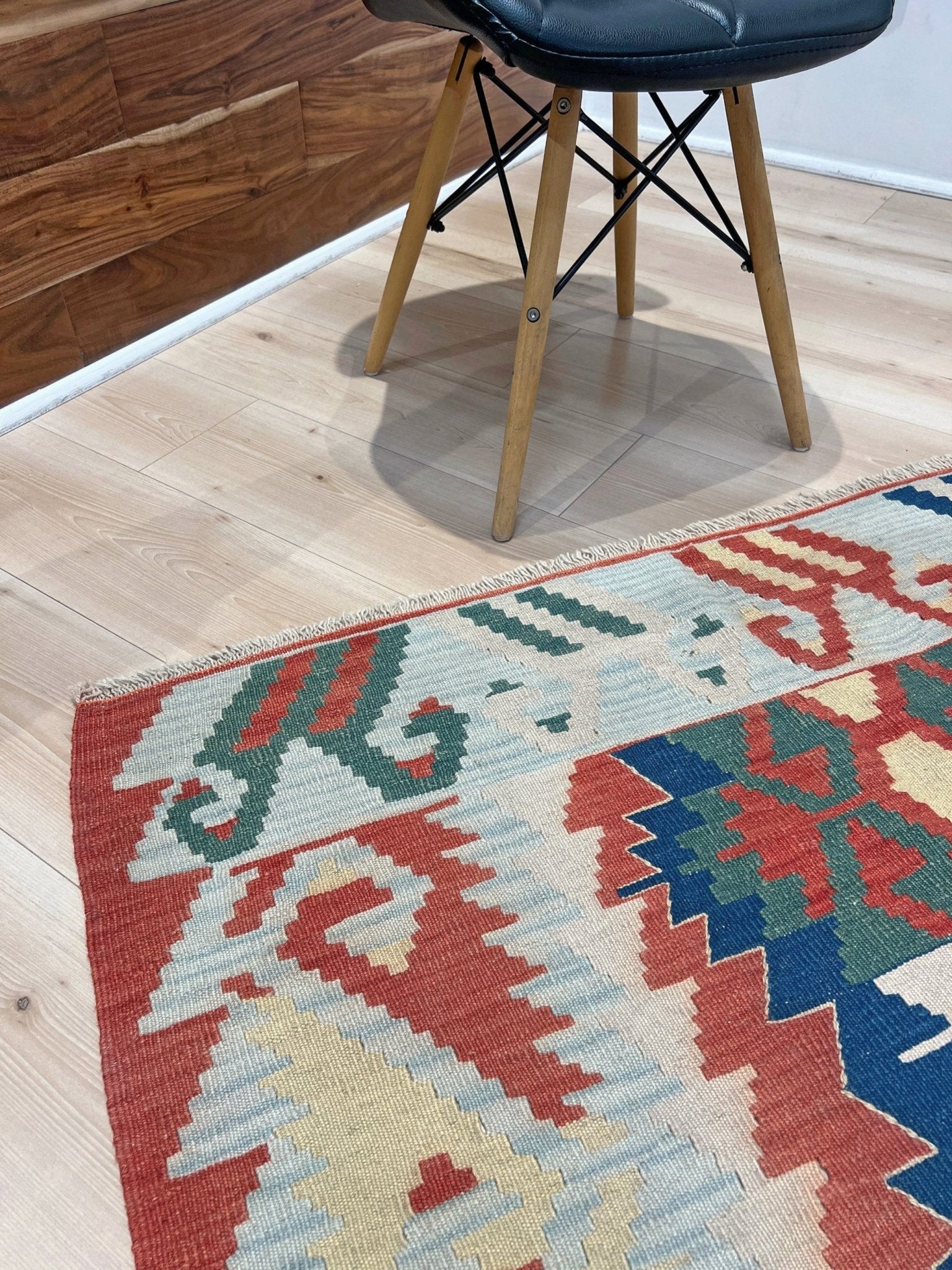 Woven turkish kilim rug with geometric pattern featuring red, blue, and beige colors. 