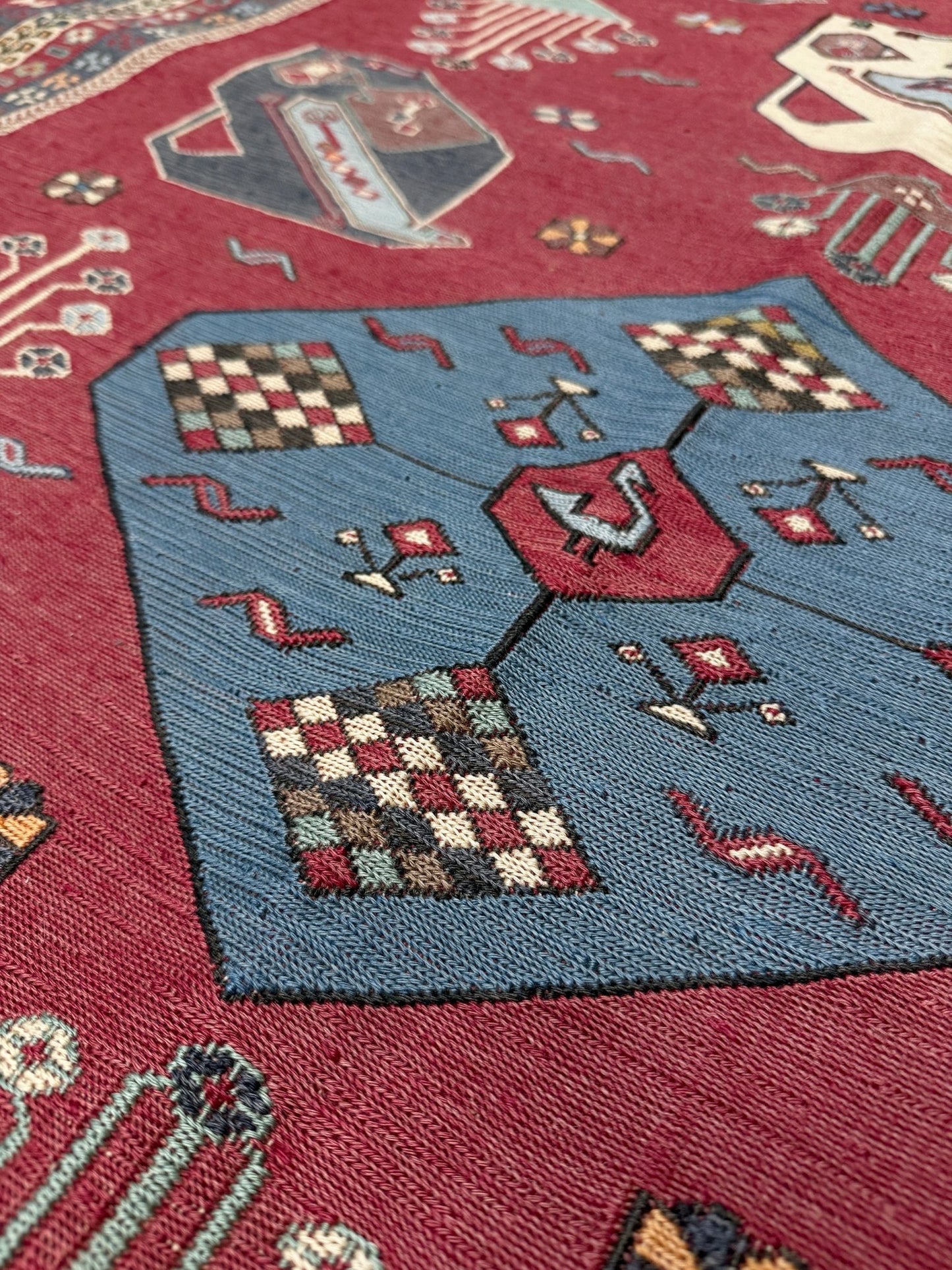 Close-up of a patterned rug with geometric designs on a red background. Vintage Armenian soumak rug with pictorial motifs in madder red, slate blue, ivory, and charcoal, 4x6 size.