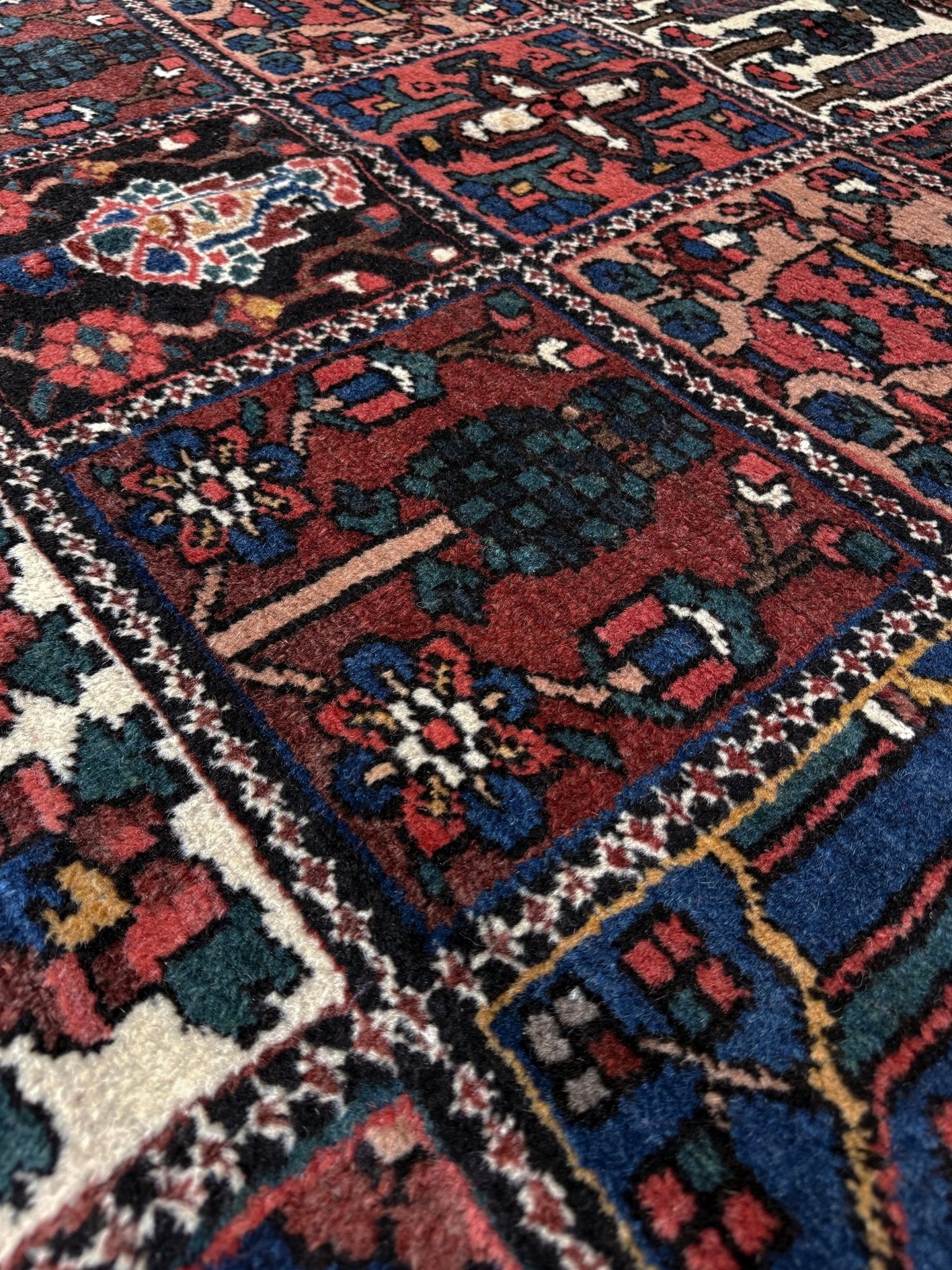 10x13 handmade Persian Bakhtiari vintage rug with garden panel design, floral motifs, and red and navy tones — shown in living room at Indigo Rugs, Burlingame — San Francisco Bay Area with free shipping