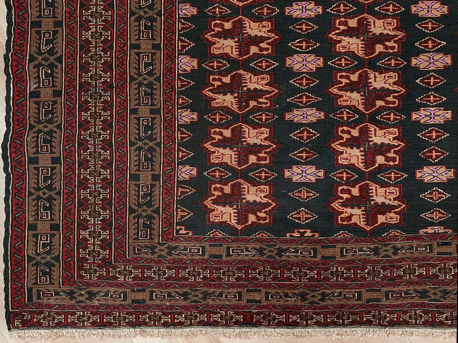 Vintage Caucasian Soumak flatweave rug with charcoal gray field, madder red rose motifs, and intricate tribal borders — handmade wool wall hanging from the 1950s, available at Indigo Rugs, the best rug shop in San Francisco Bay Area, Burlingame CA.