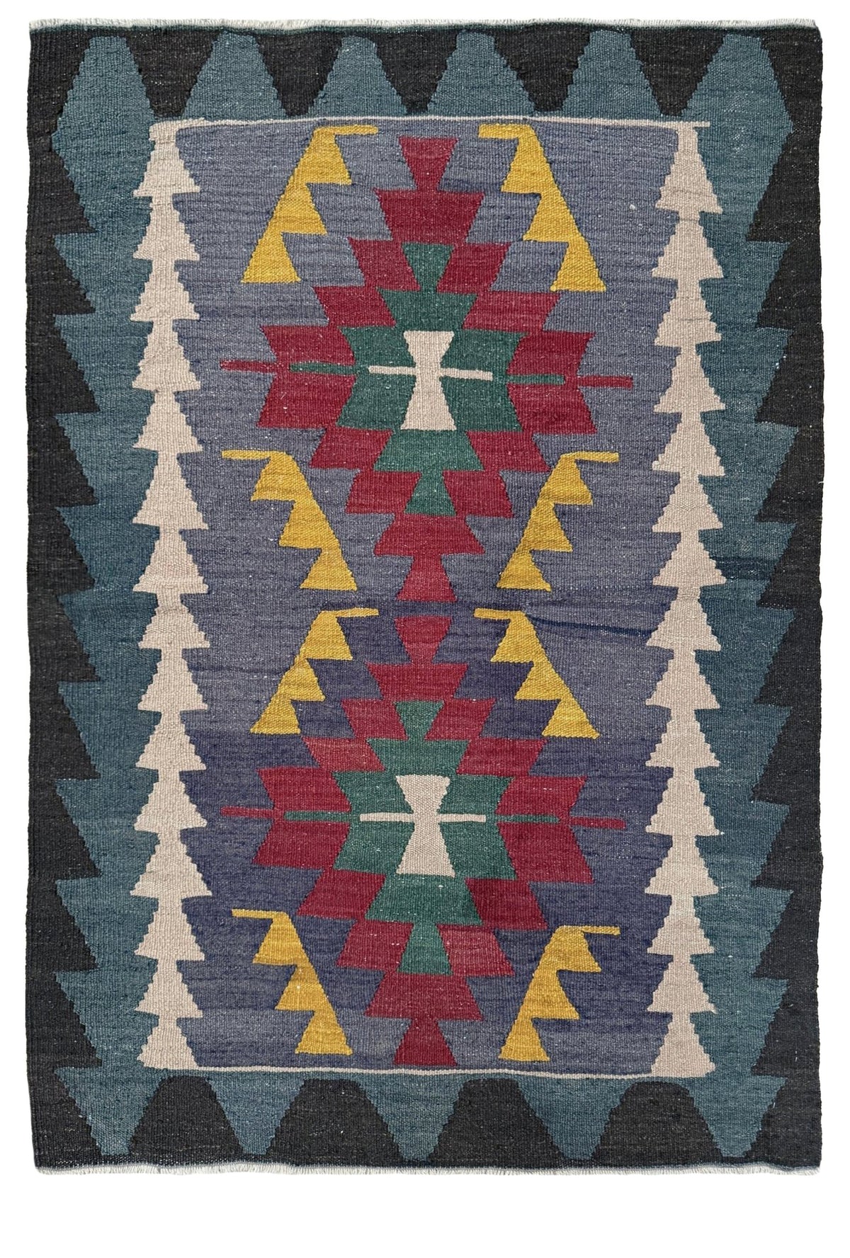A square woven rug with a Southwestern geometric pattern, featuring a central diamond motif in red, green, and yellow on a slate blue background, surrounded by dark gray and cream triangular borders.
