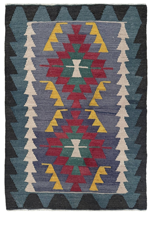 A square woven rug with a Southwestern geometric pattern, featuring a central diamond motif in red, green, and yellow on a slate blue background, surrounded by dark gray and cream triangular borders.