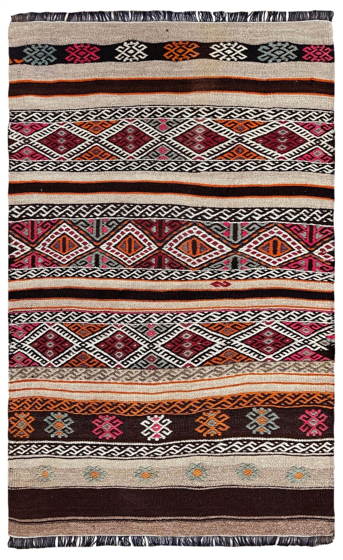 A flatweave kilim rug with a complex geometric pattern featuring multiple horizontal bands of diamonds, zigzags, and floral motifs in red, orange, pink, black, white, and beige.