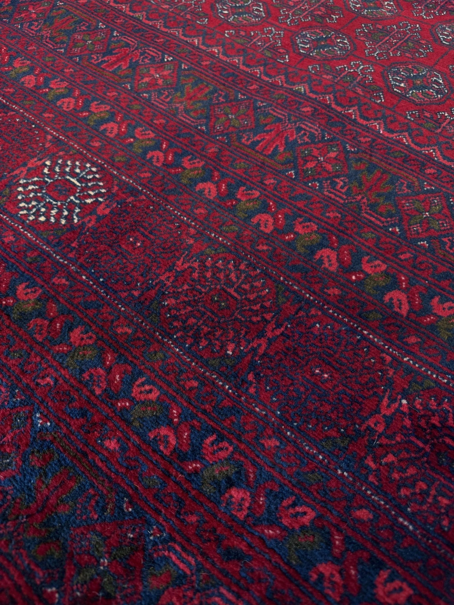 Traditional Turkmen Khoja Roshnai rug with crimson field, repeating gul motifs, navy borders, handmade merino wool area rug 7x10 with velvety pile from Indigo Rugs Burlingame Bay Area.